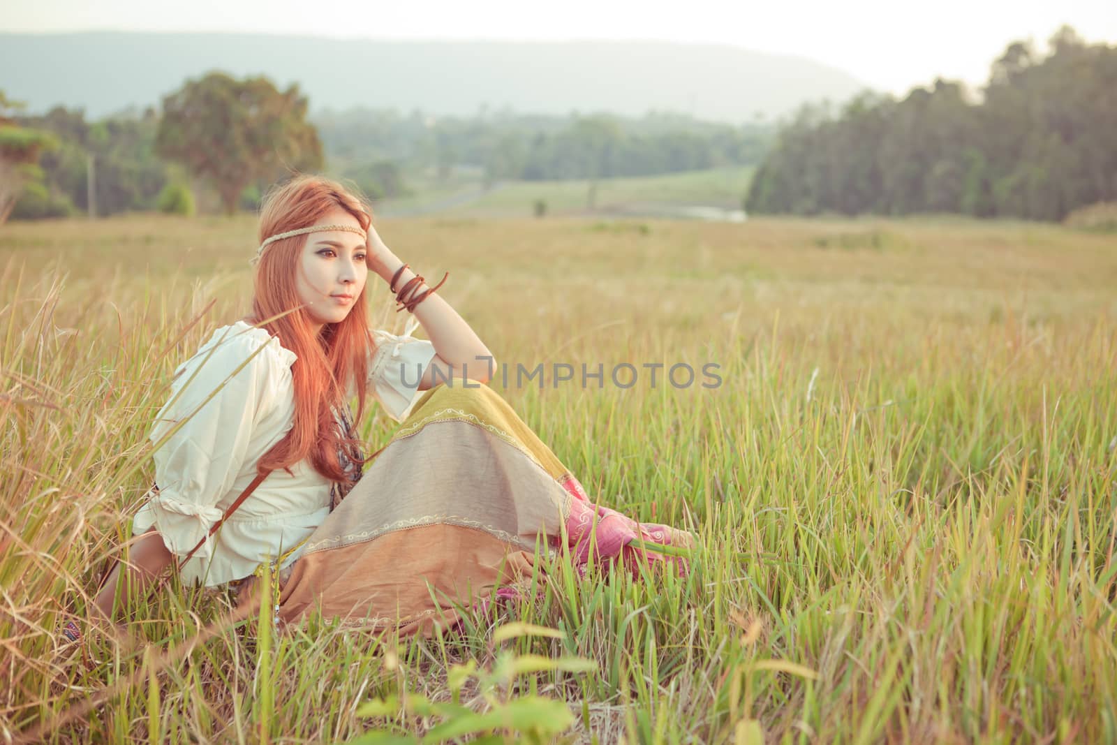 Country hippie girl sitting at golden field