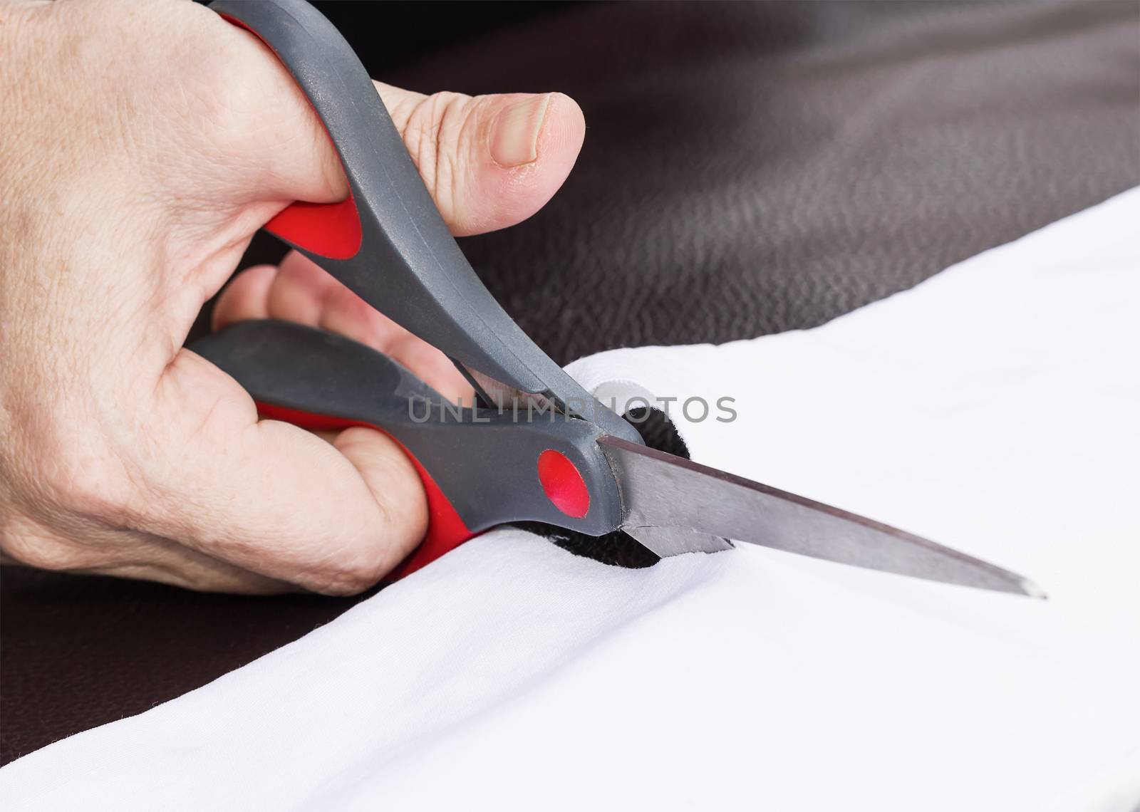 Hand cut white fabric with scissors of dressmaker cutting a cloth