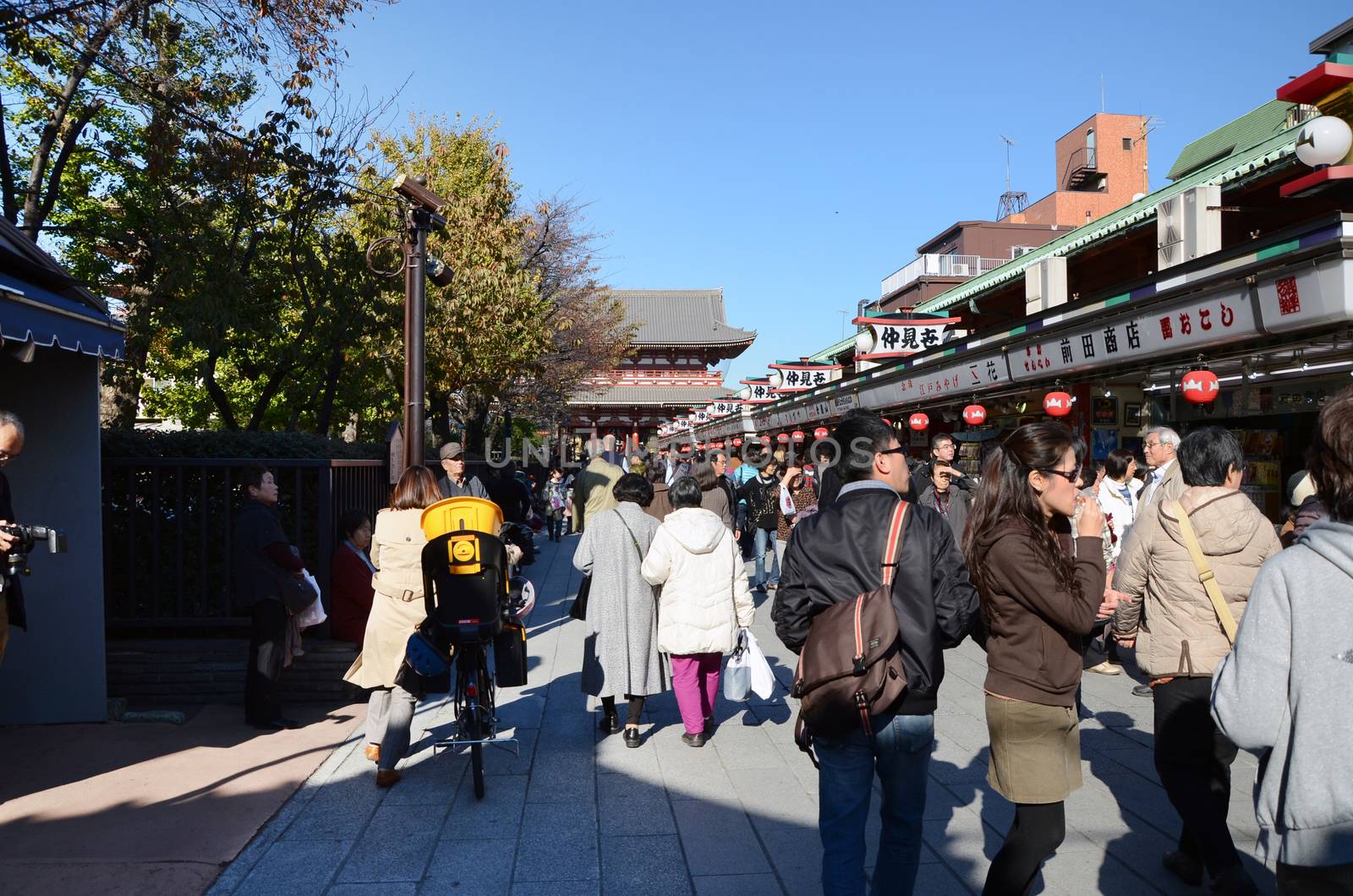 TOKYO, JAPAN - NOV 21 : Tourists visit Nakamise shopping street in Asakusa, Tokyo on 21 November 2013. The busy arcade connects Senso-ji Temple to it's outer gate Kaminarimon, which can just be seen in the distance. 