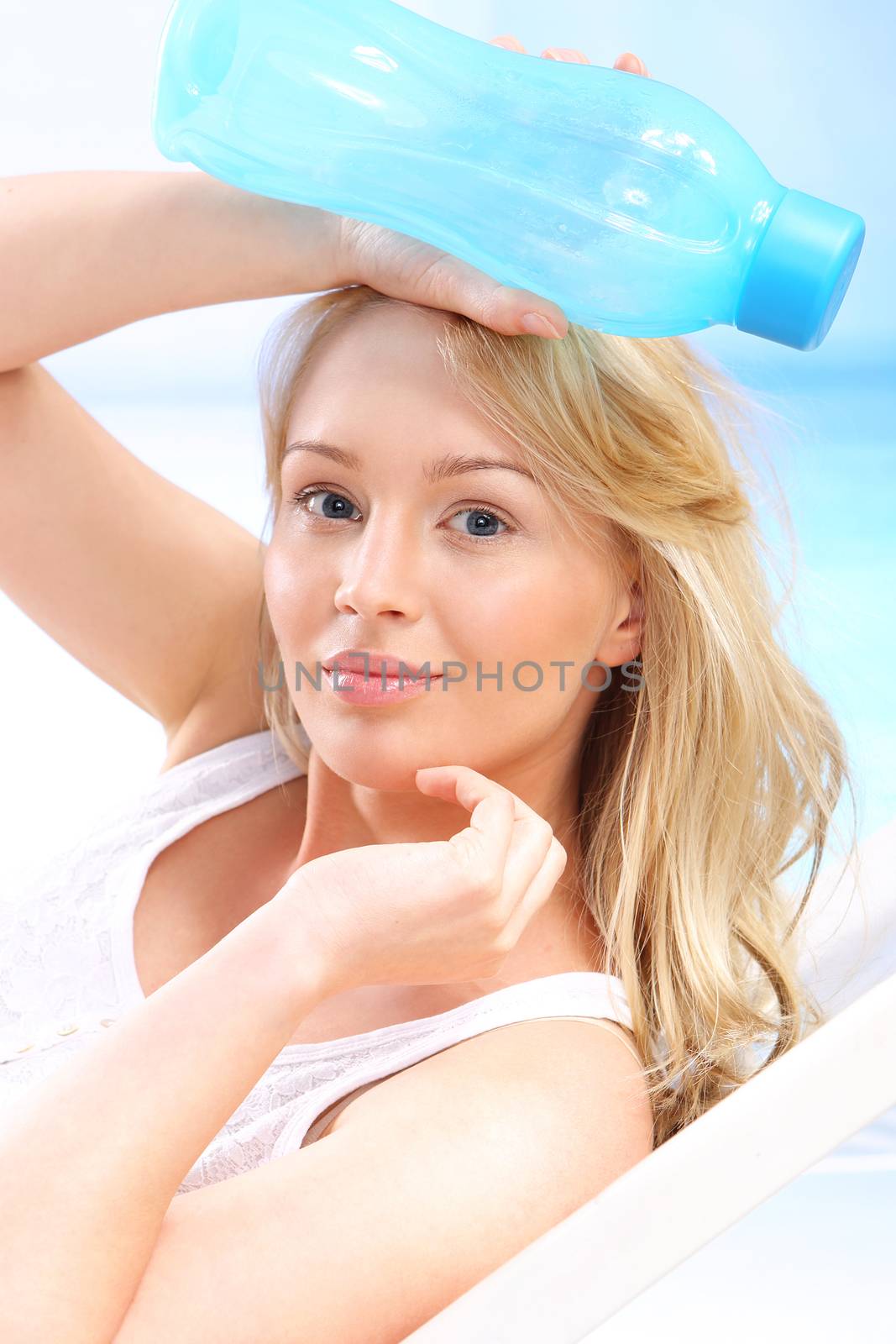 Young attractive woman on a deck chair with a bottle of water on a sunny ocean