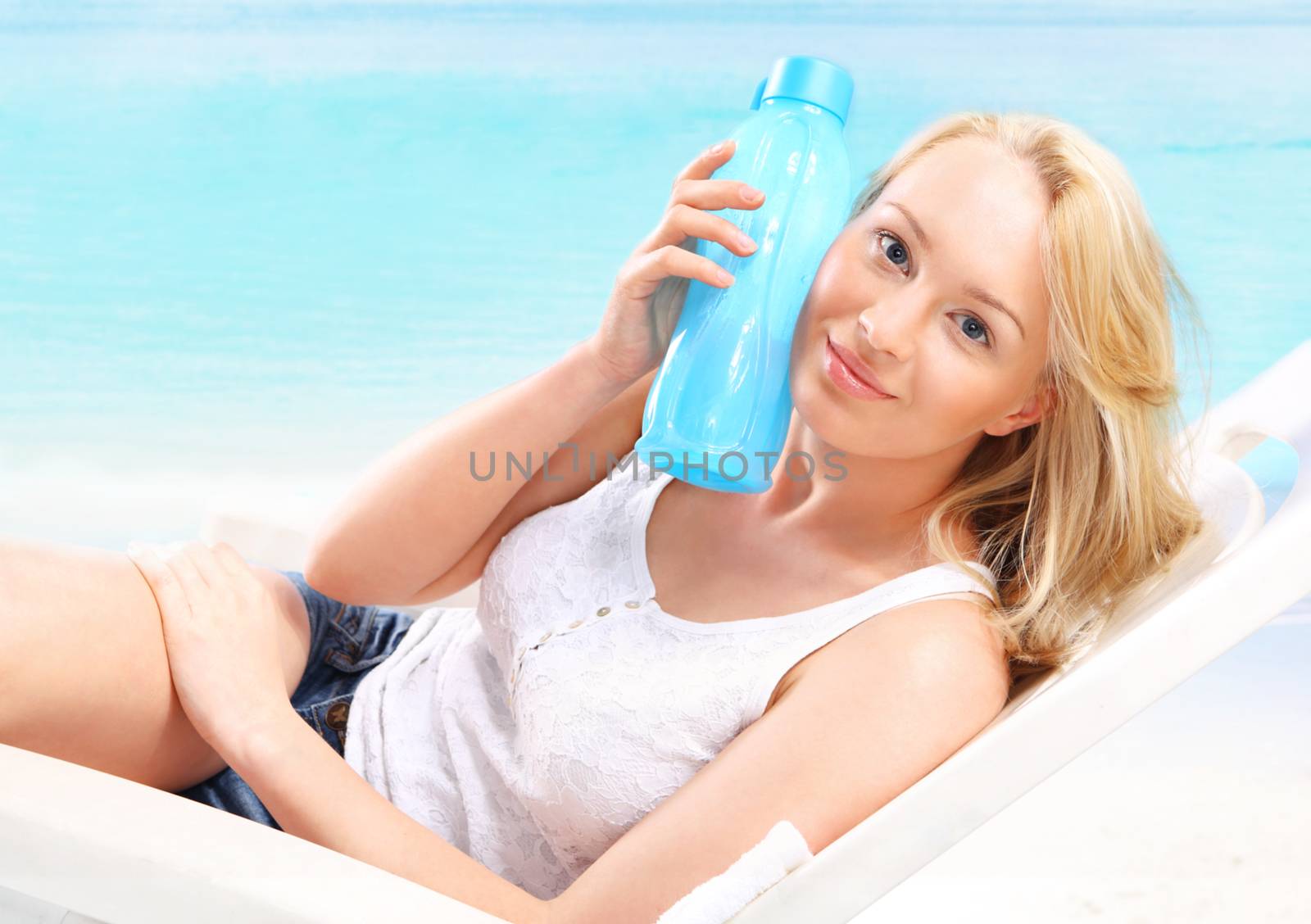 Woman with bottle of water on beach by robert_przybysz