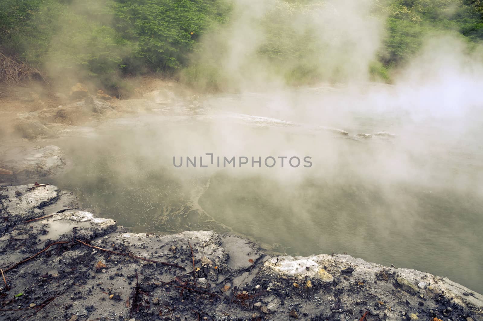 natural hot basin with steam over it in volcanic area of Hokkaido island