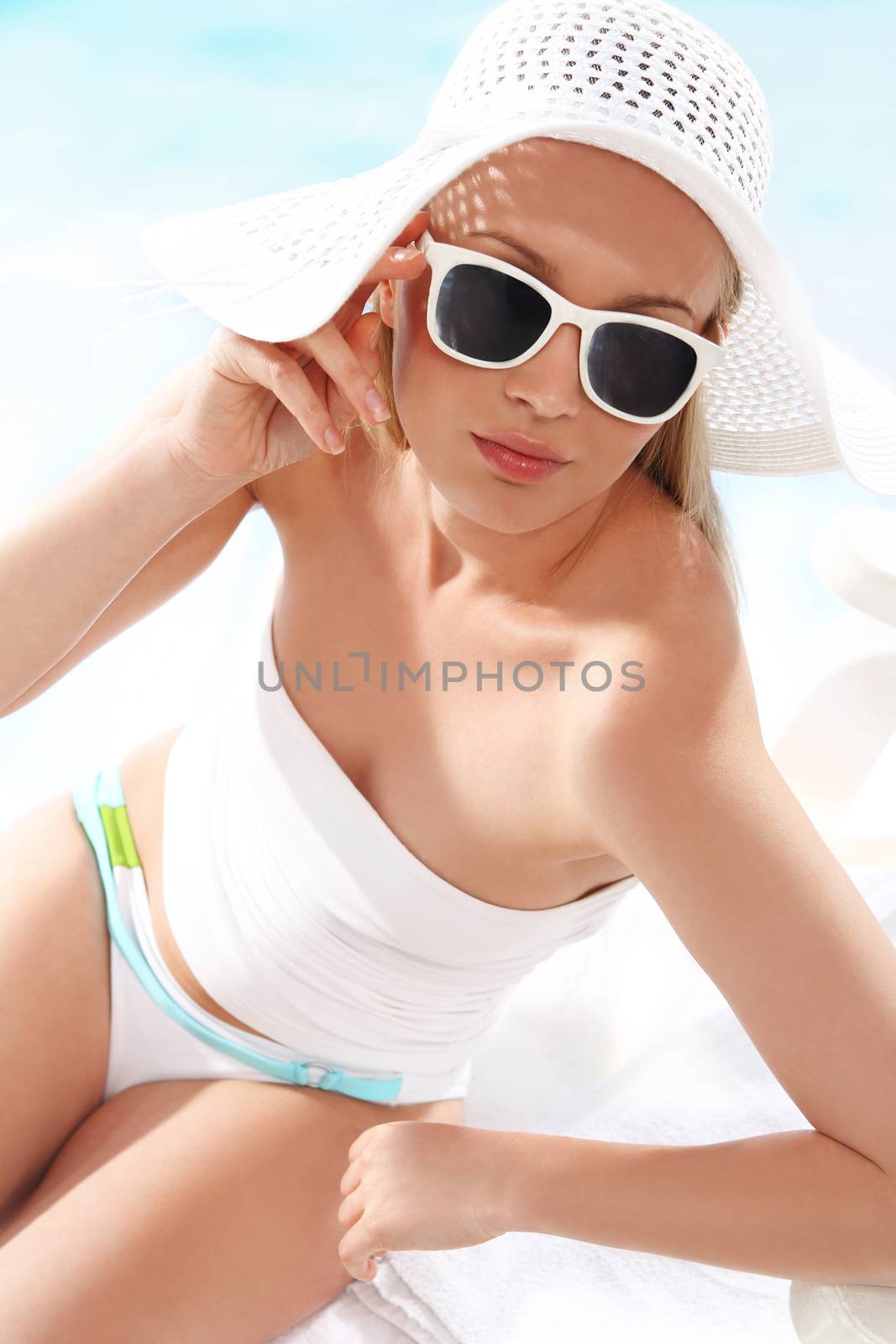 Beautiful, attractive girl in costume and hat relaxing on a sunny beach.