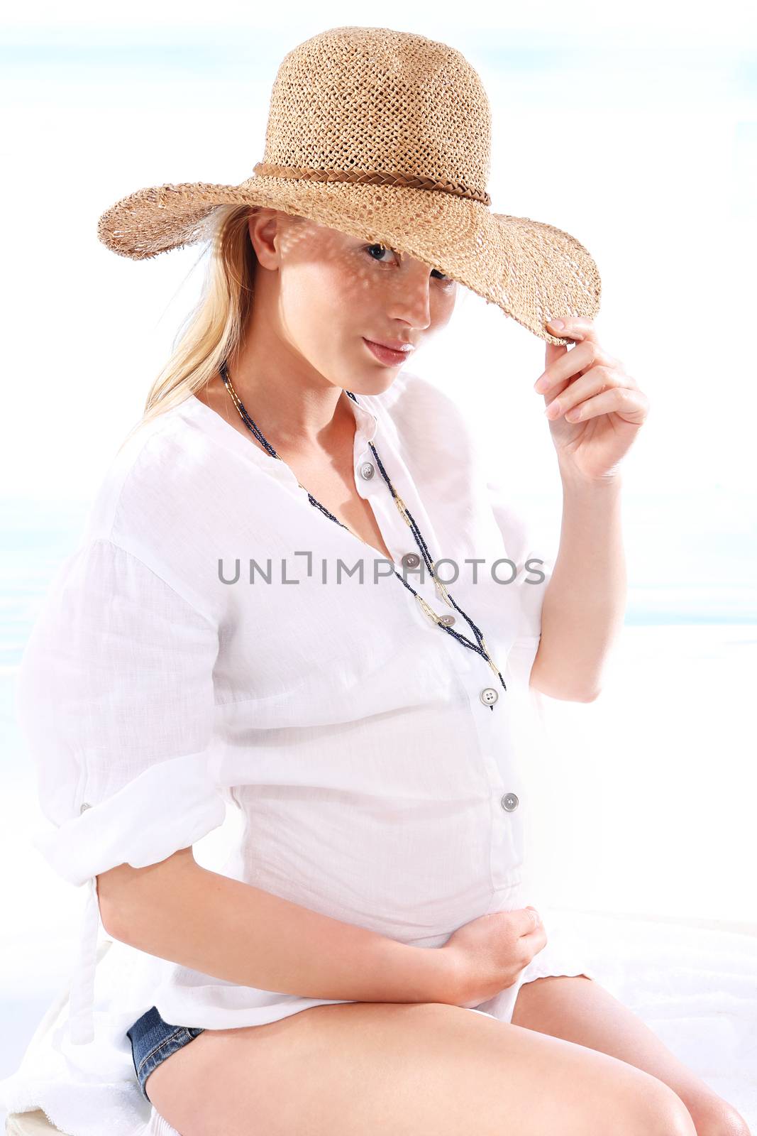 Pregnant woman sitting in a deck chair and sun bathing