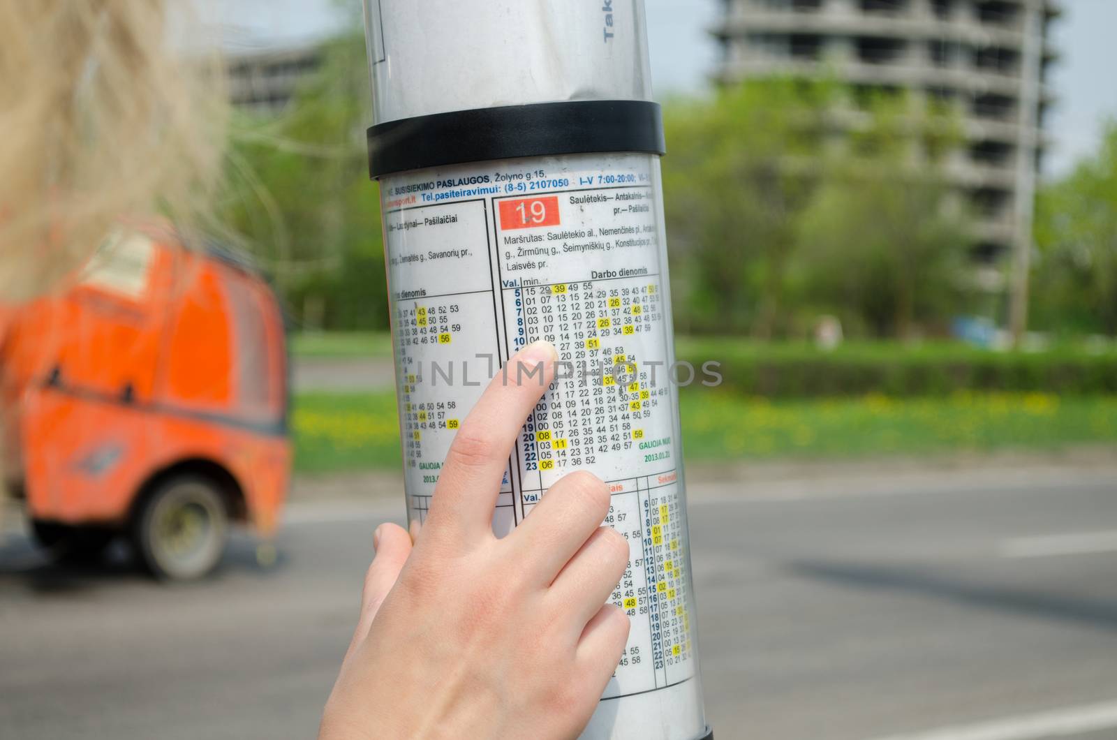 bus driving schedule under a glass hood and hand of woman