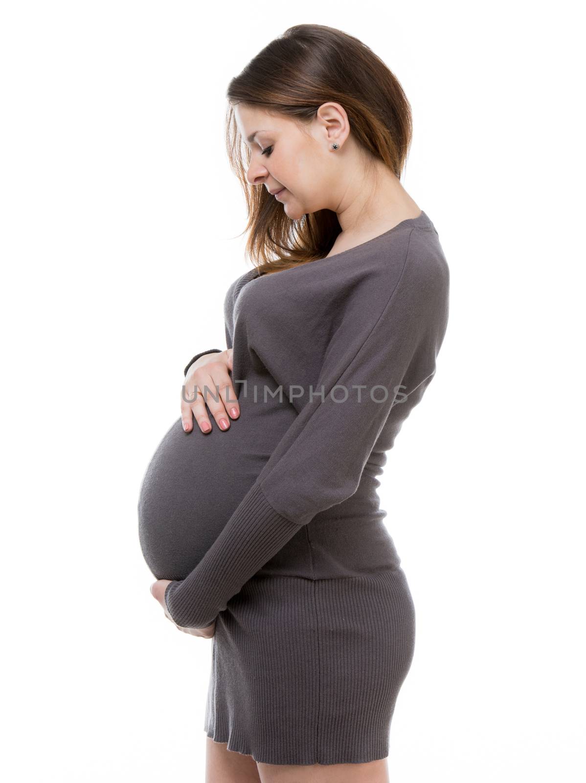 beautiful pregnant girl in a grey dress hugging her belly on white background