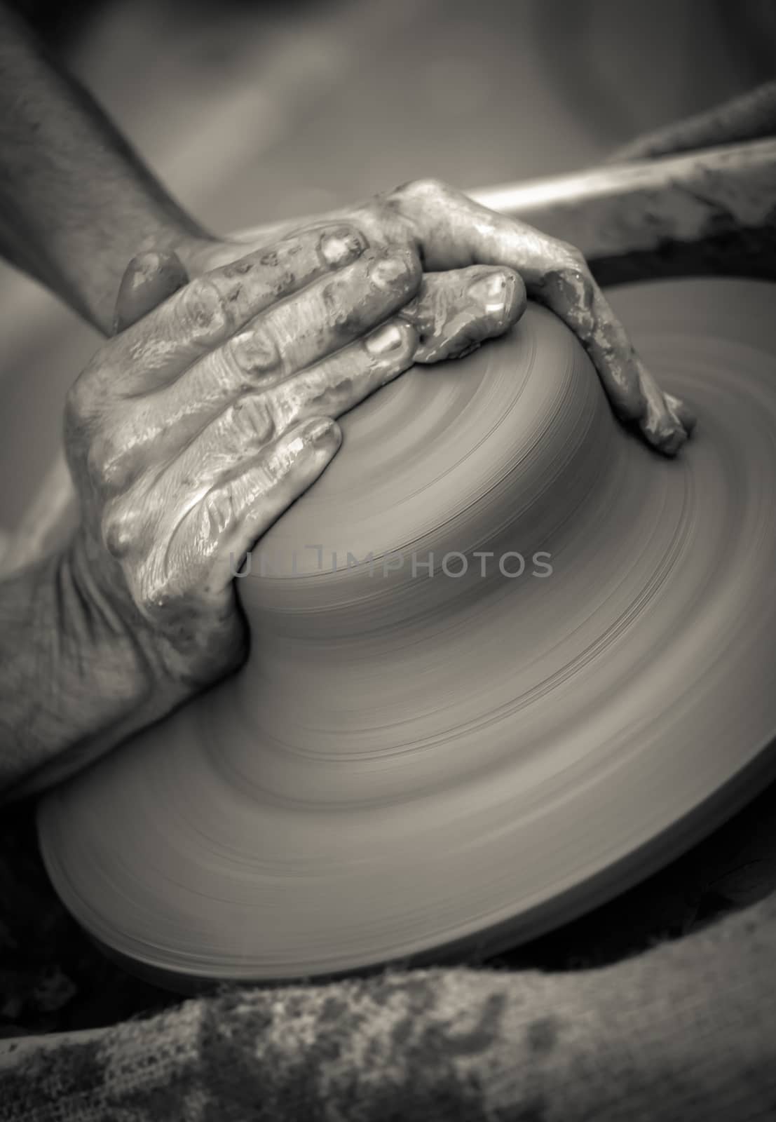 Hands working on pottery wheel , close up retro style toned photo wit shallow DOF