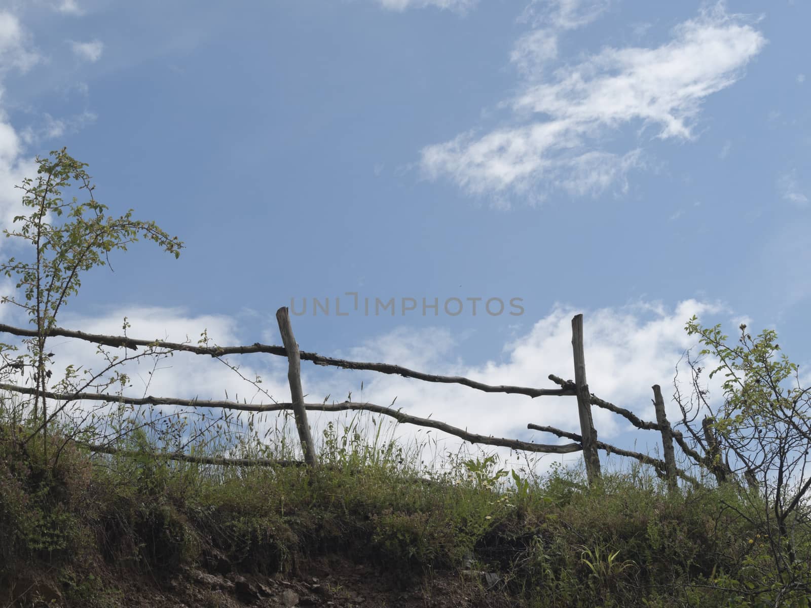 Sky, clouds and old wooden fence near the road