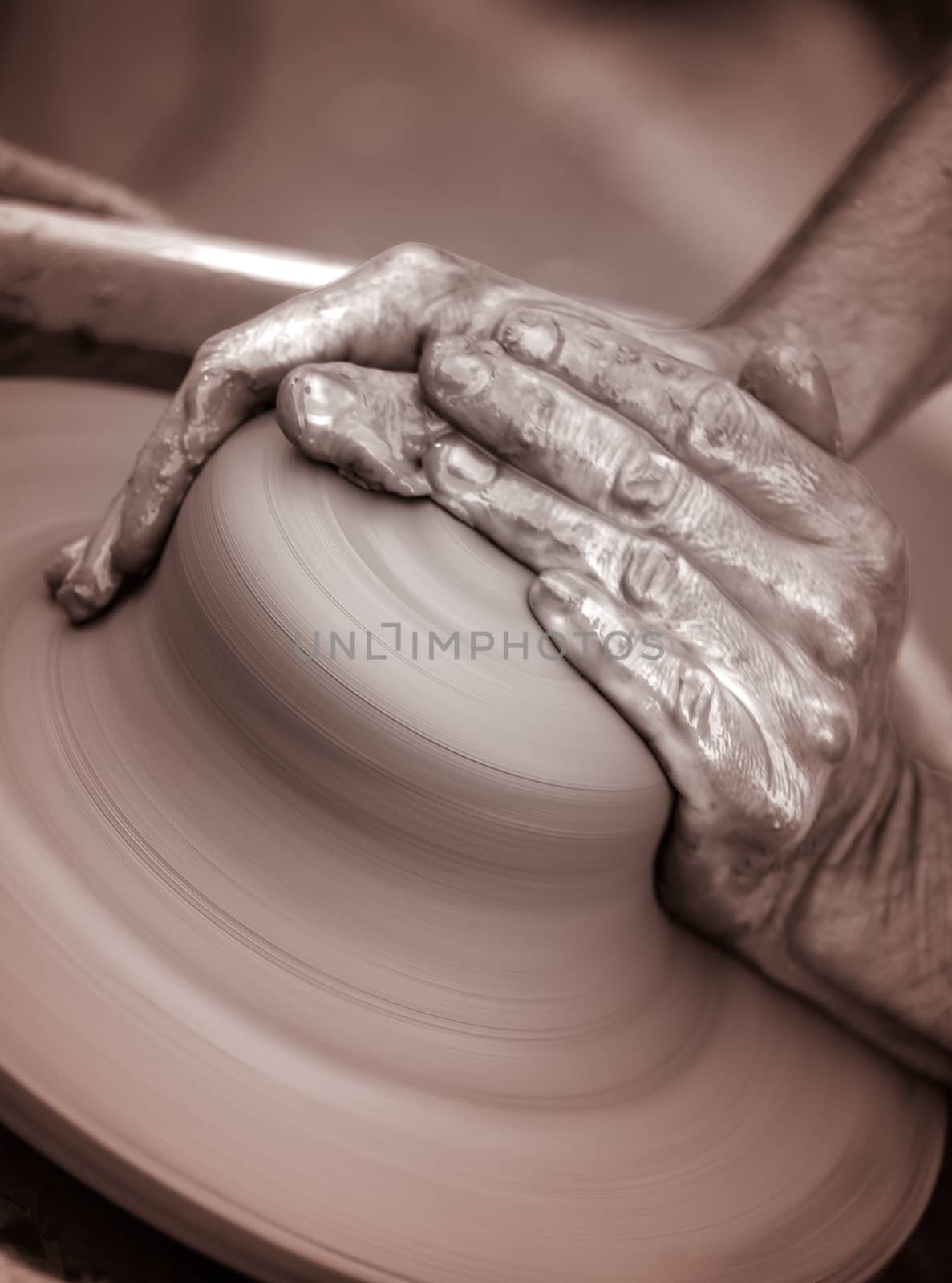 Hands working on pottery wheel , close up retro style toned photo wit shallow DOF