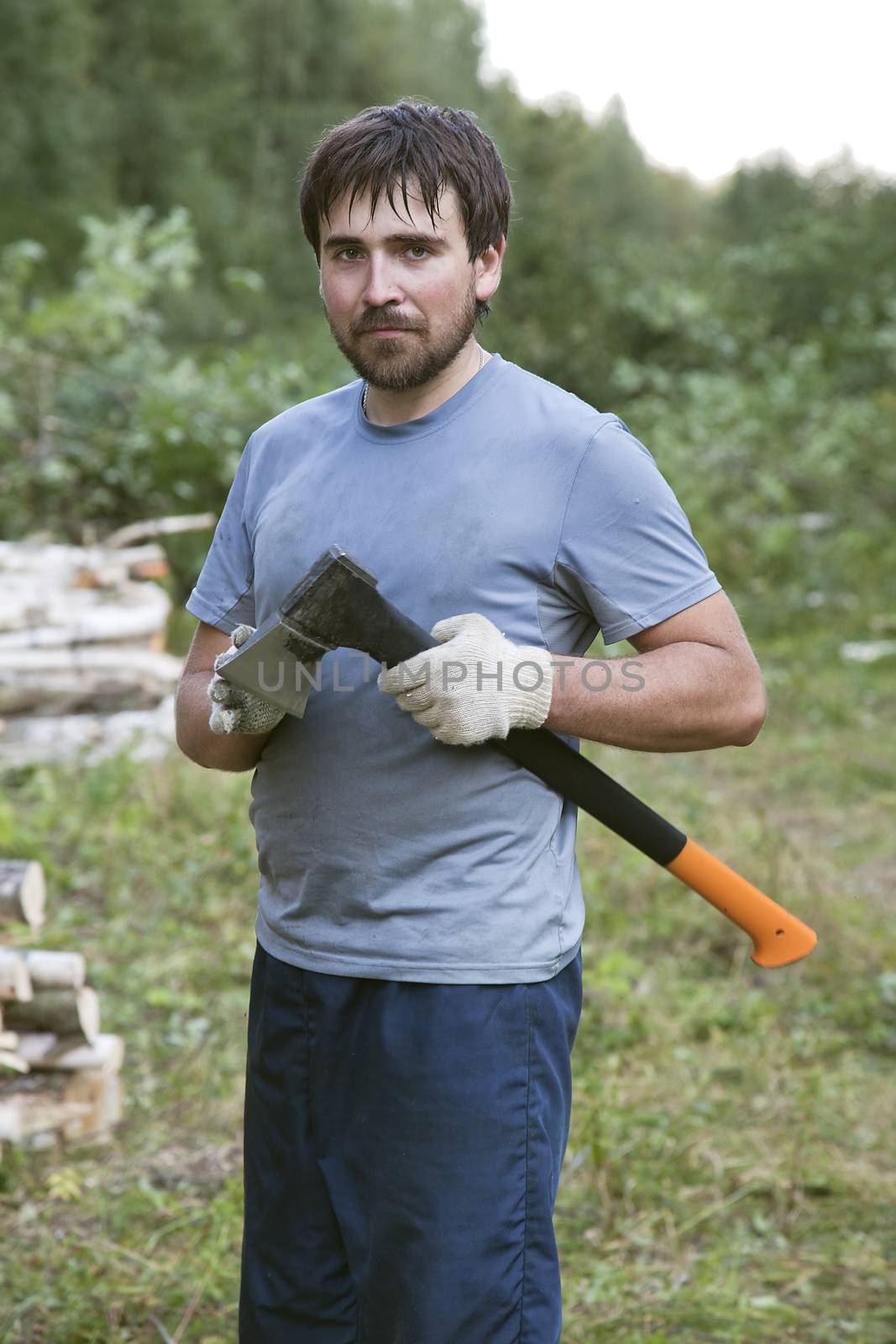 Young lumberman in a forest with an axe in his hands 