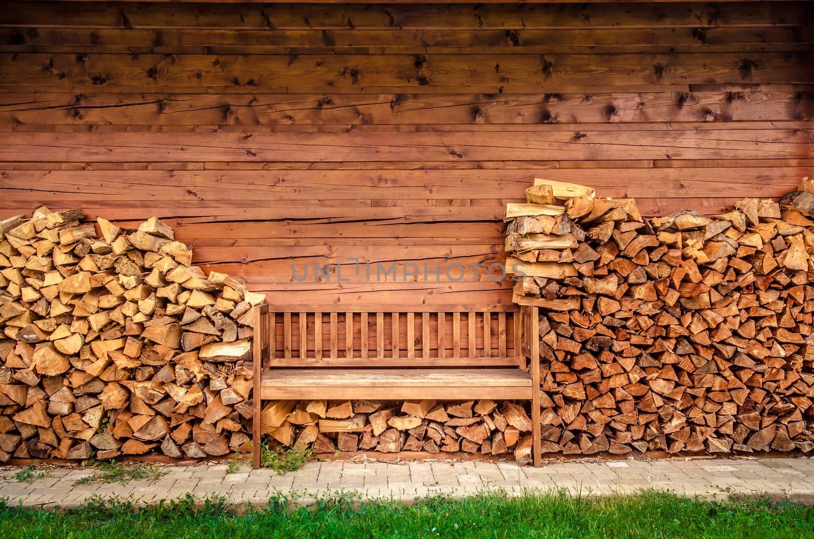 Detail of empty wooden bench with pile of firewood