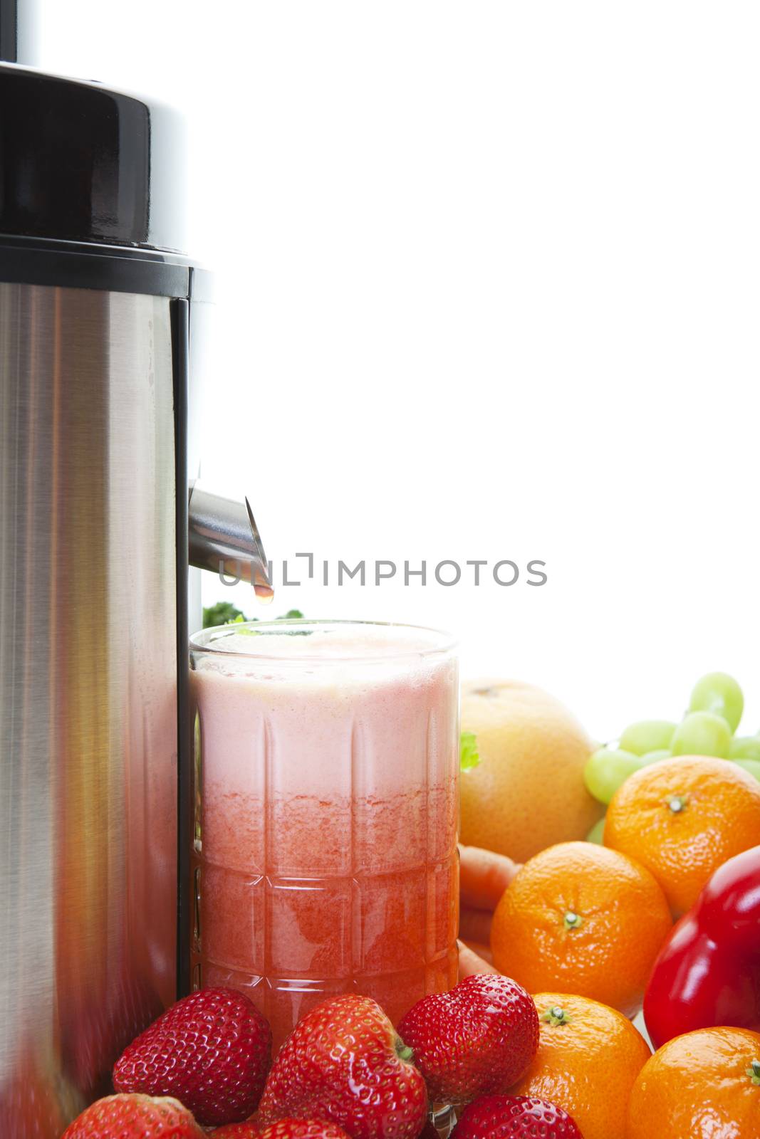 A glass of freshly squeezed juice under a still dripping spout.  Shot on white background.