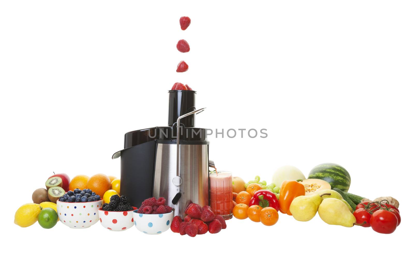 Sweet, ripe strawberries fall into the juicing machine hopper, and the extracted juice flows into the glass.  Shot on white background.