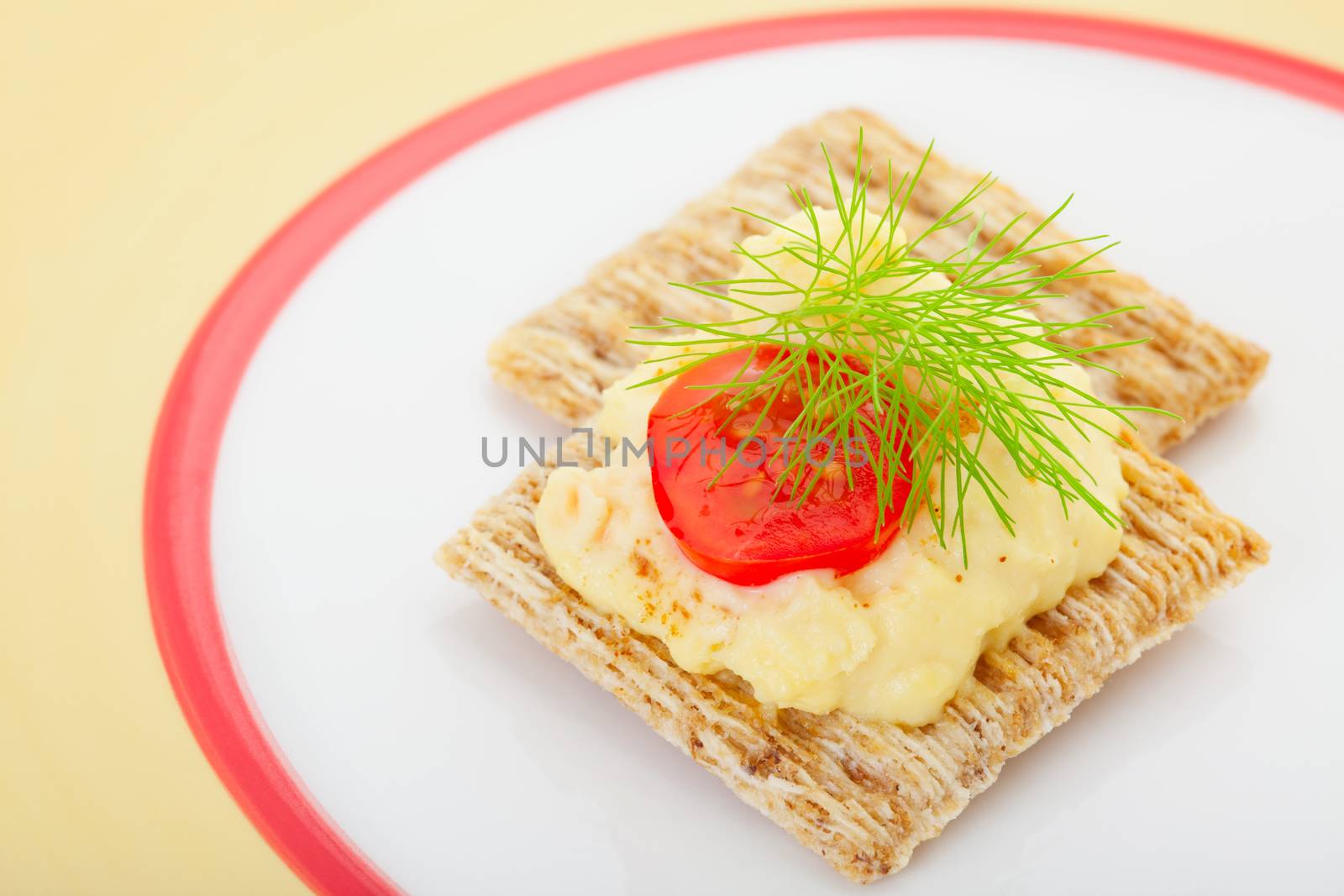 Rosemary and olive oil crackers topped with creamy deviled egg filling, baby tomato, a dash of paprika, and finished with a garnish of fine, fresh fennel.