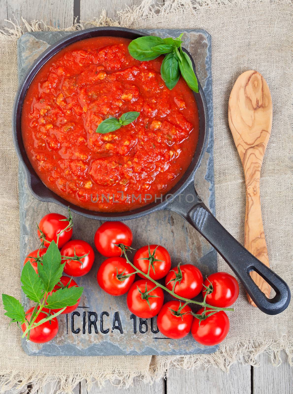 A cast iron pan filled with tomato sauce made from organic, heirloom tomatoes, resting on a piece of vintage salvaged slate, circa 1804.