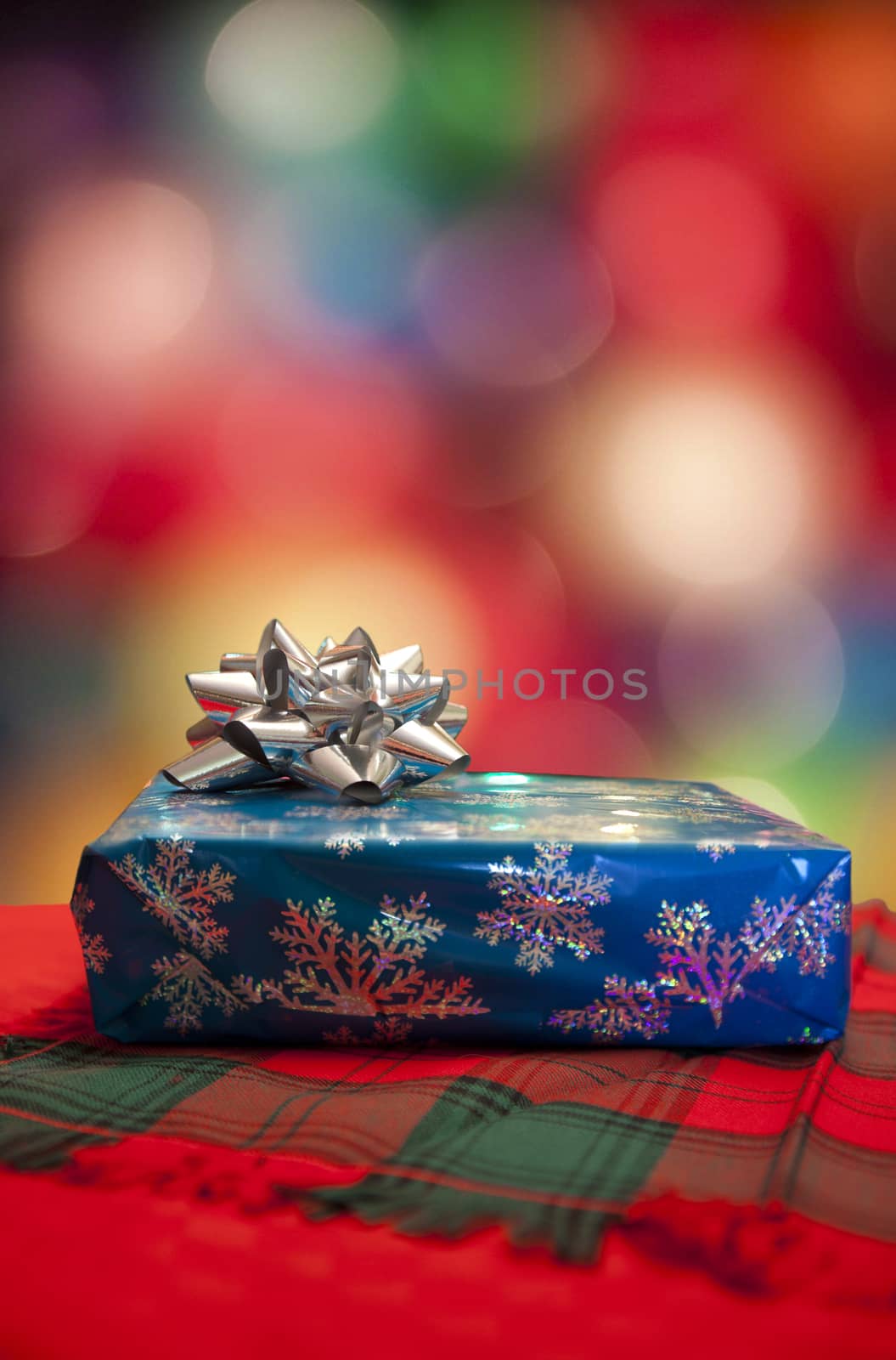 Wrapped Christmas gift with the soft bokeh of tree lights behind.
