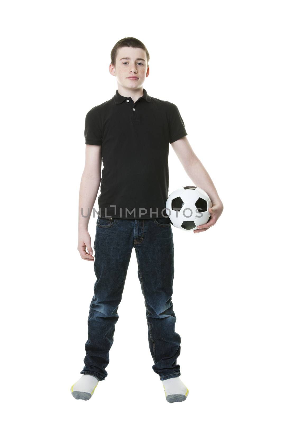 A thirteen year old boy dressed in jeans and t-shirt and holding a soccer ball.  Shot on white background.