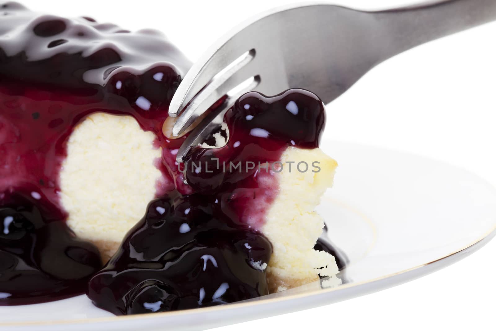 A fork sliding into a fresh piece of blueberry cheesecake.  Shot on white background.