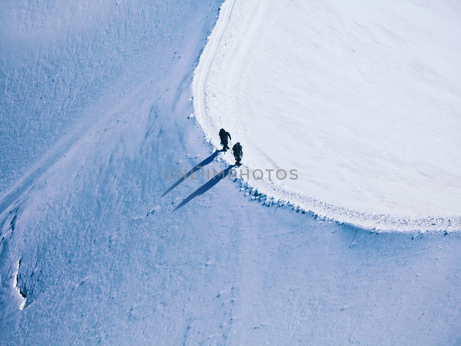 unrecognizable two climbers on the way to a mountain peak in the Alps