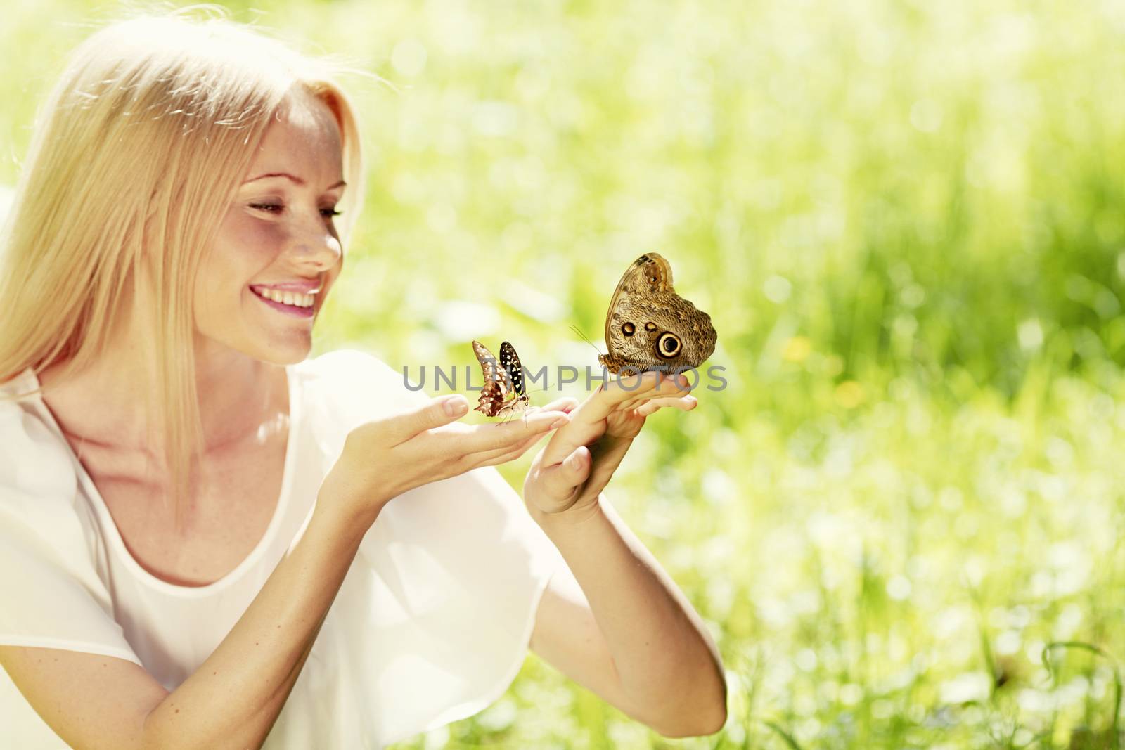 Beautiful young happy Woman playing with butterfly outdoors