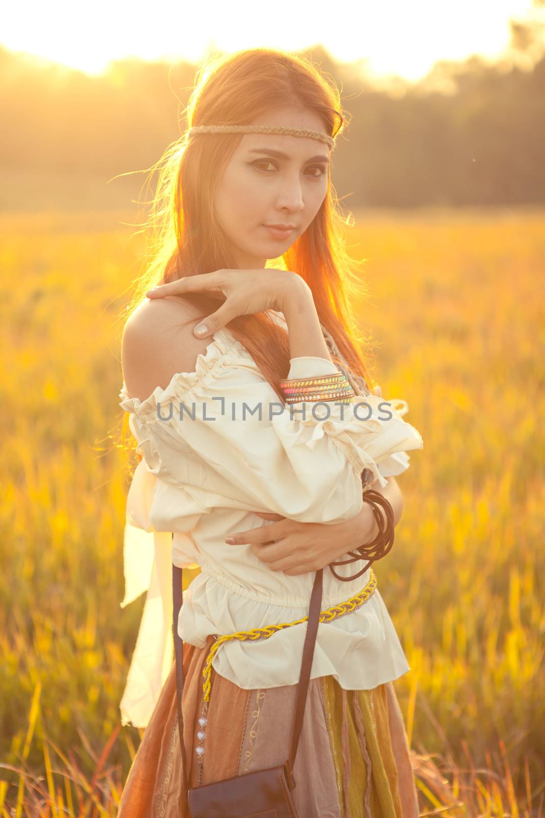 Hippie woman posing in golden field on sunset