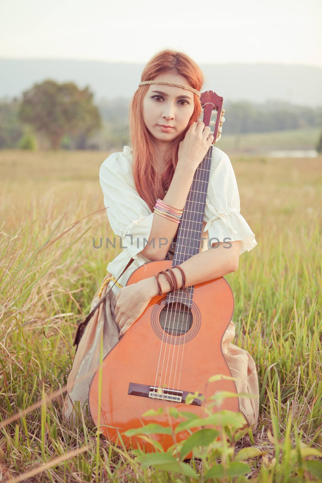 Hippie girl playing guitar on grass by witthaya