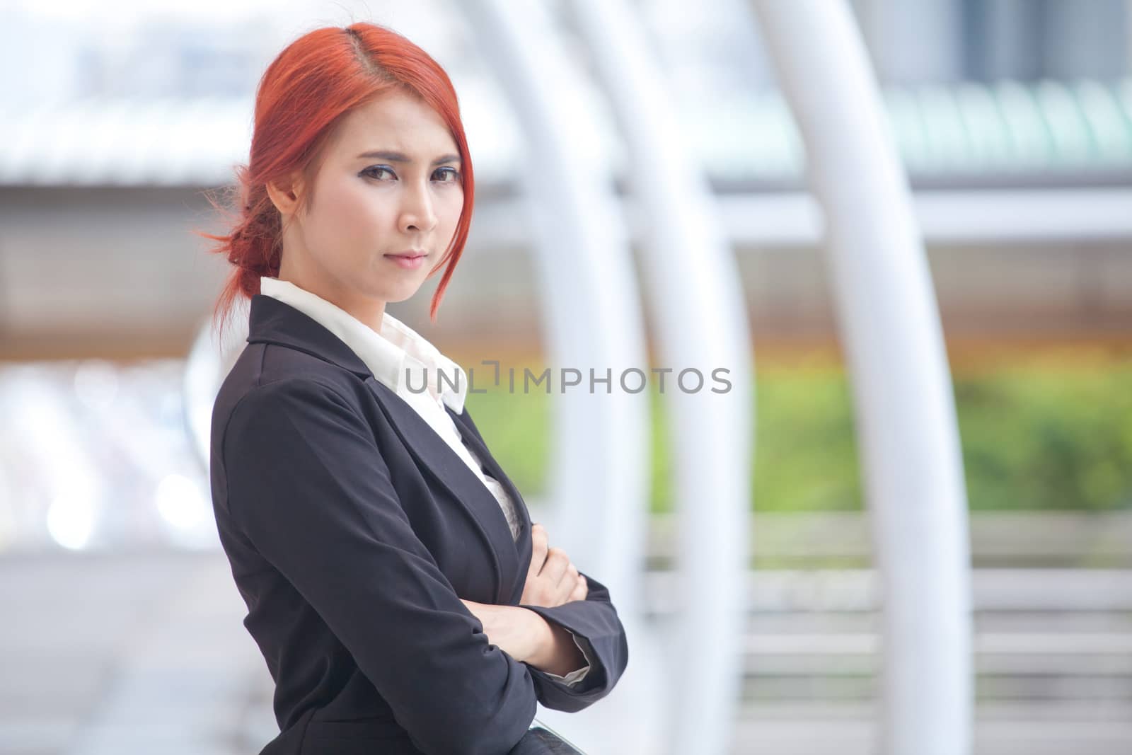 Portrait of young business asian woman standing and smiling arms crossed in modern city