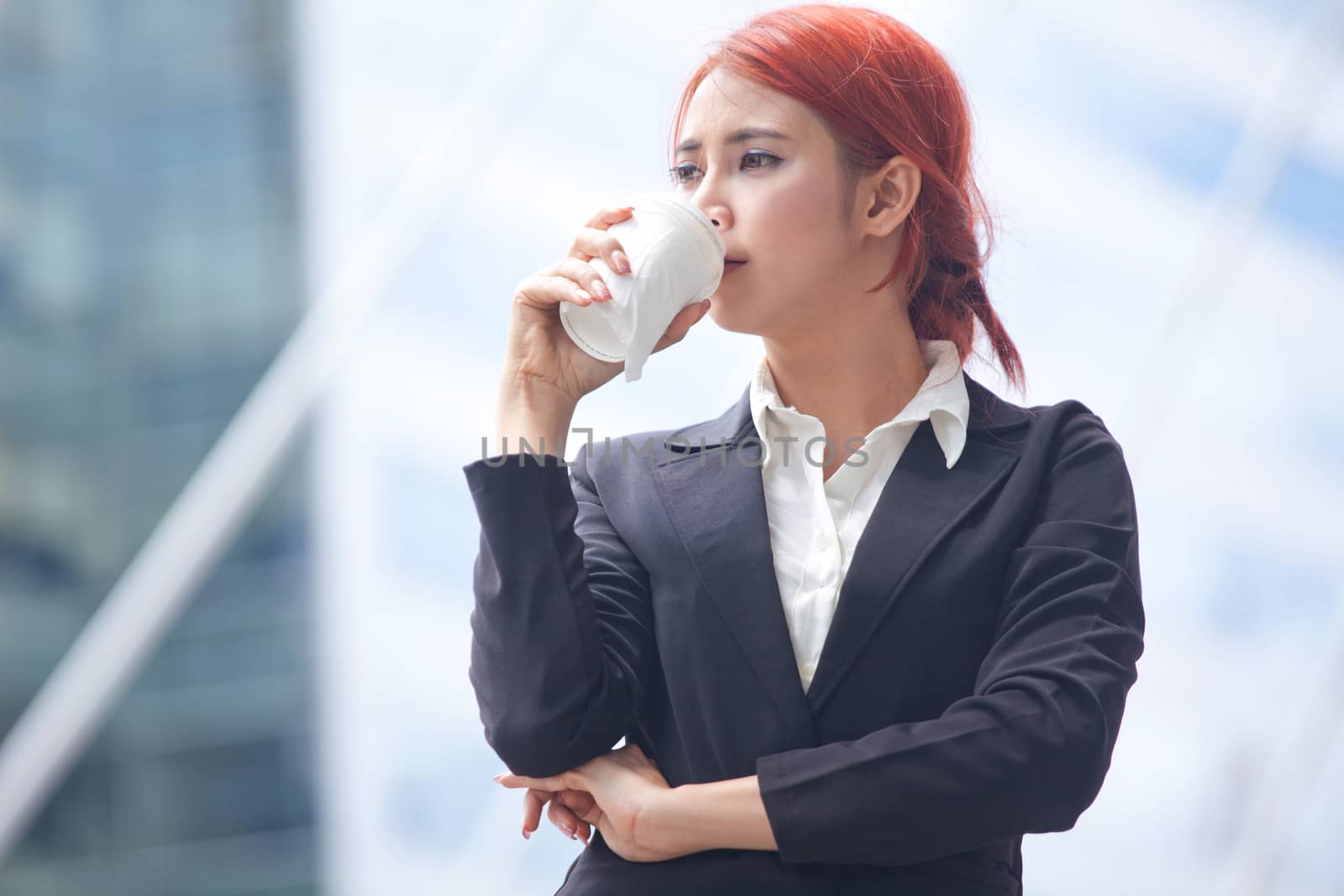 Portrait of young business asian woman standing with coffee in modern city