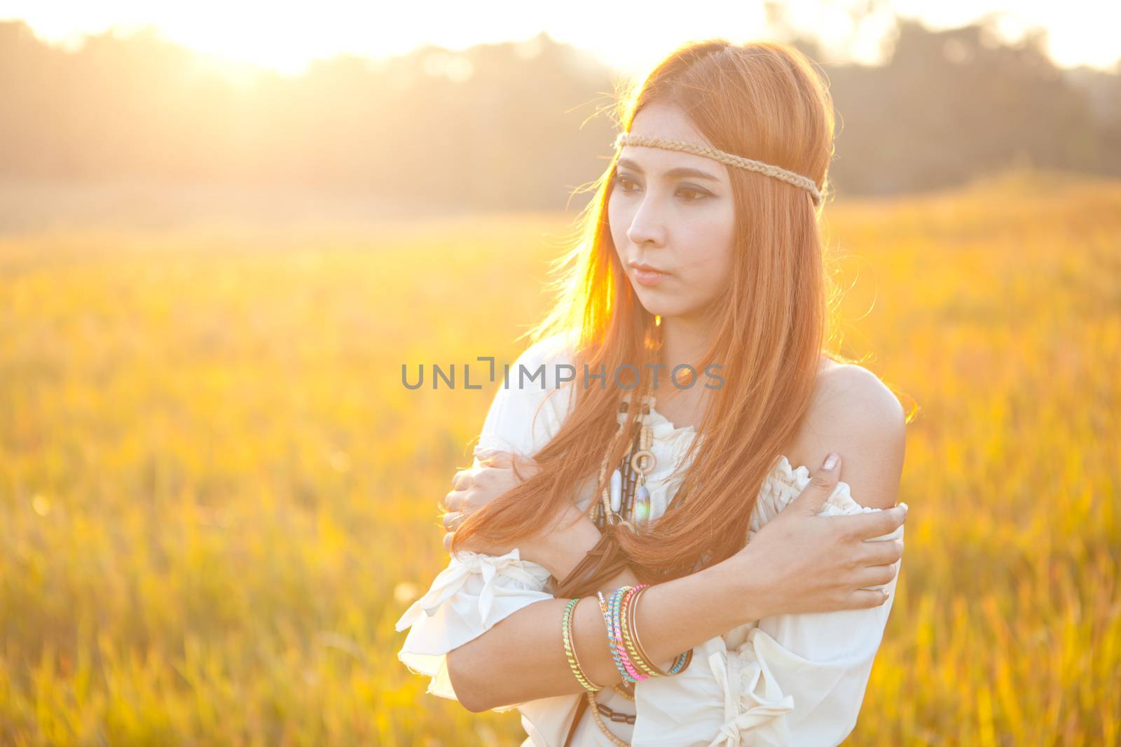 Hippie woman posing in golden field on sunset