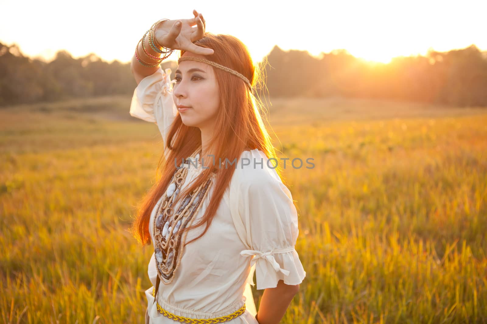 Hippie woman posing in golden field on sunset