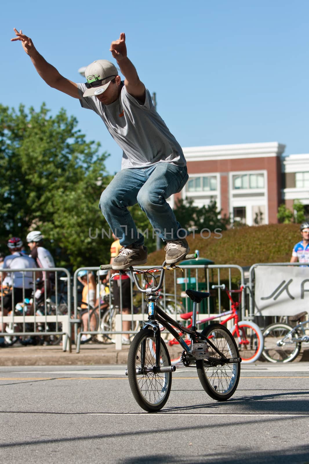 Athens, GA, USA - April 26, 2014:  A young man practices standing on the handlebars of his bike before the start of the BMX Trans Jam competition on the streets of downtown Athens.