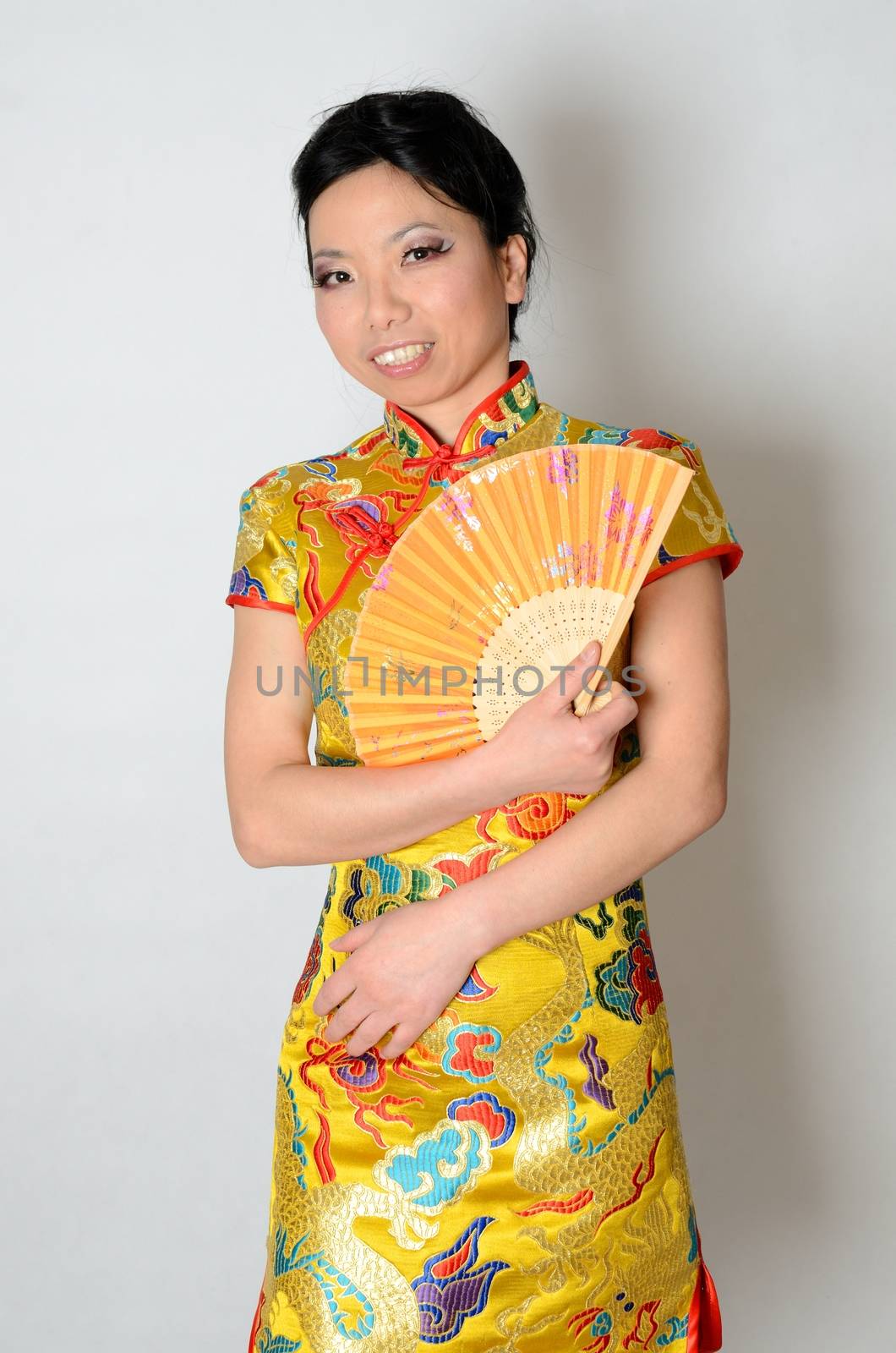 Elegant Chinese lady wearing traditional colorful dress. Kind female model from Asia holding fan in her hand. 