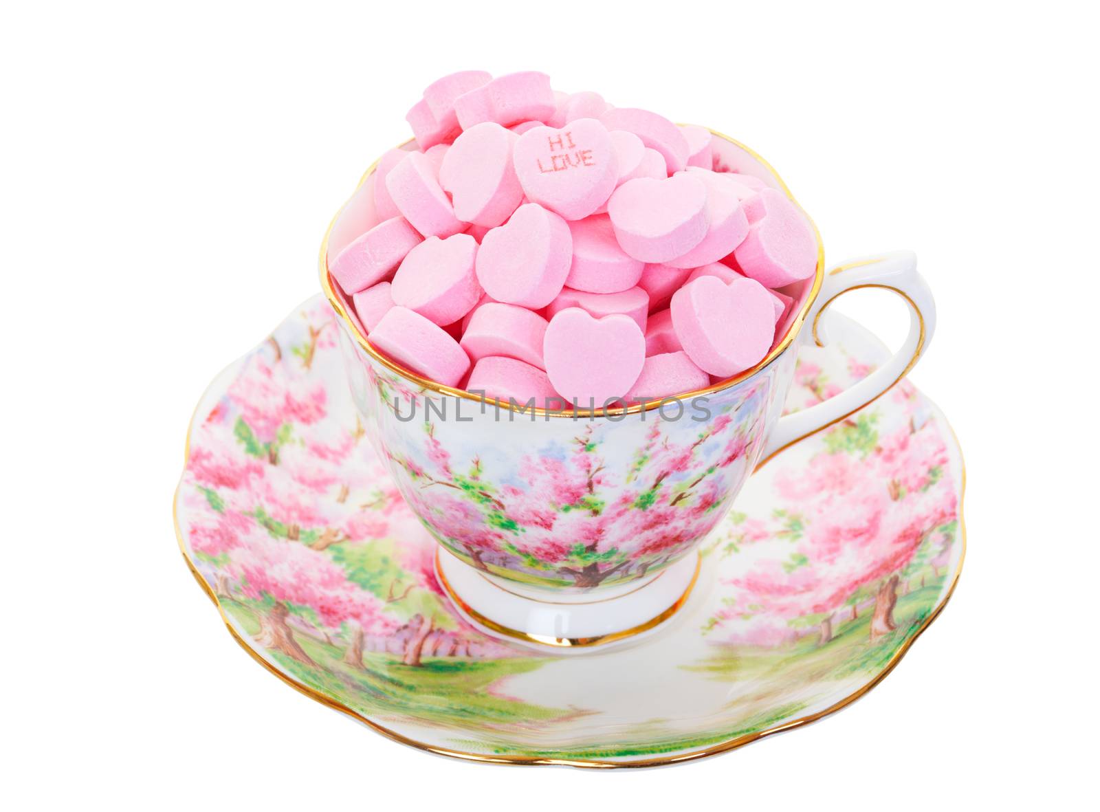 Pink candy hearts in a teacup and saucer.  Shot on white background.