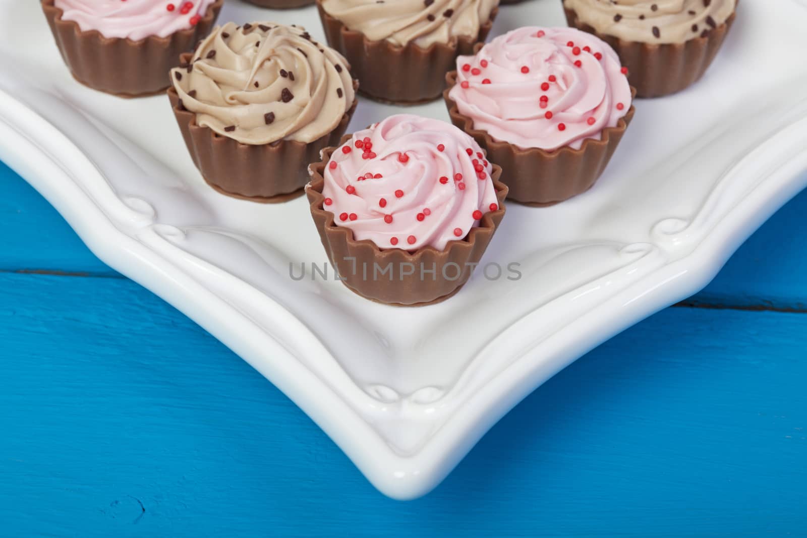 Elegant truffle filled, cupcake shaped chocolates on a white serving platter.