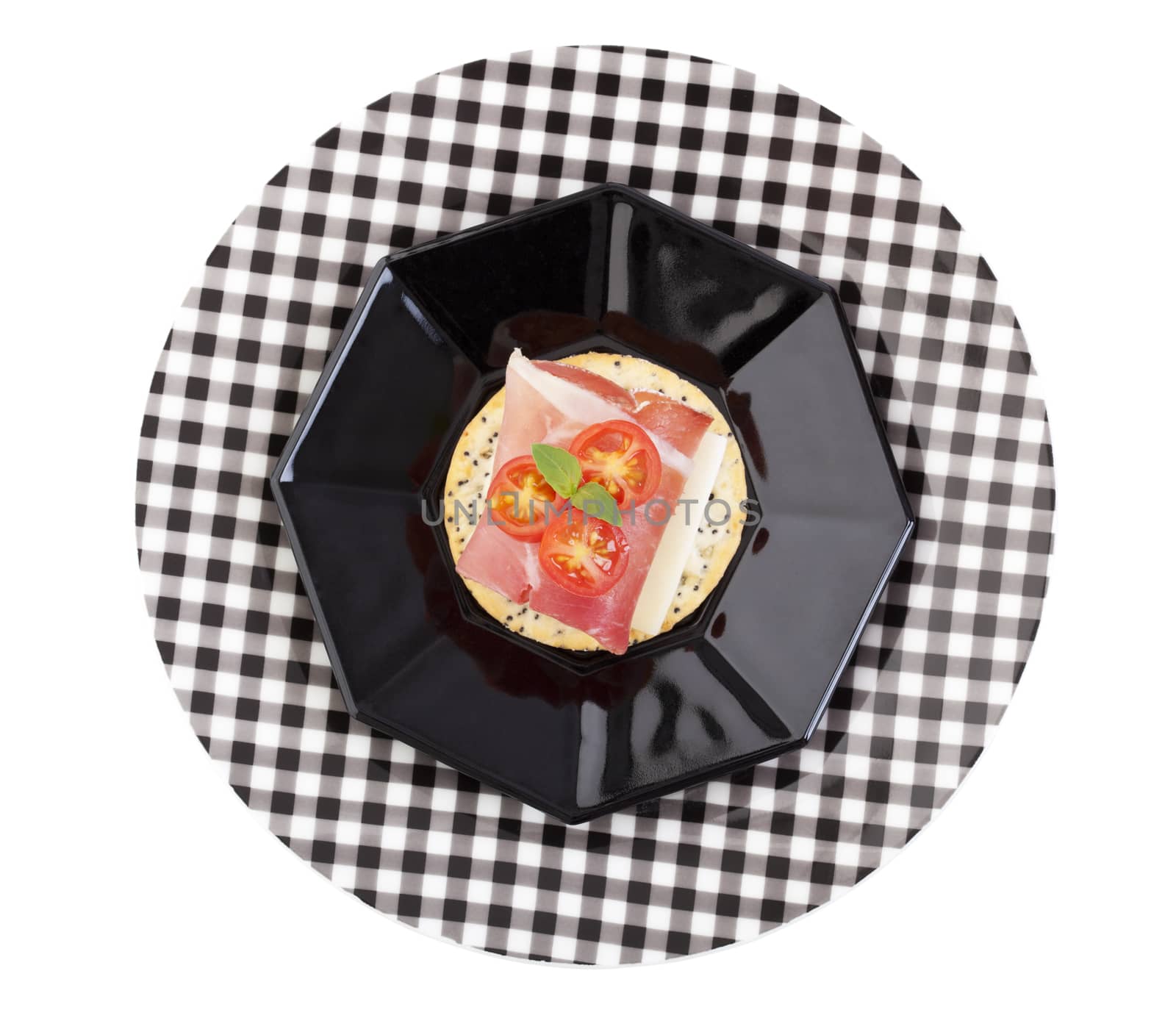 Fresh Proscuitto and Provolone cheese with baby tomato on a poppy and sesame seed cracker; garnished with a sprig of fresh basil.  Isolated with clipping path.