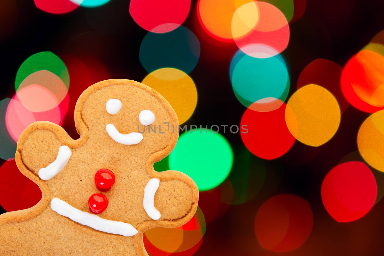 A freshly baked and decorated gingerbread man with a beautiful Christmas bokeh background.