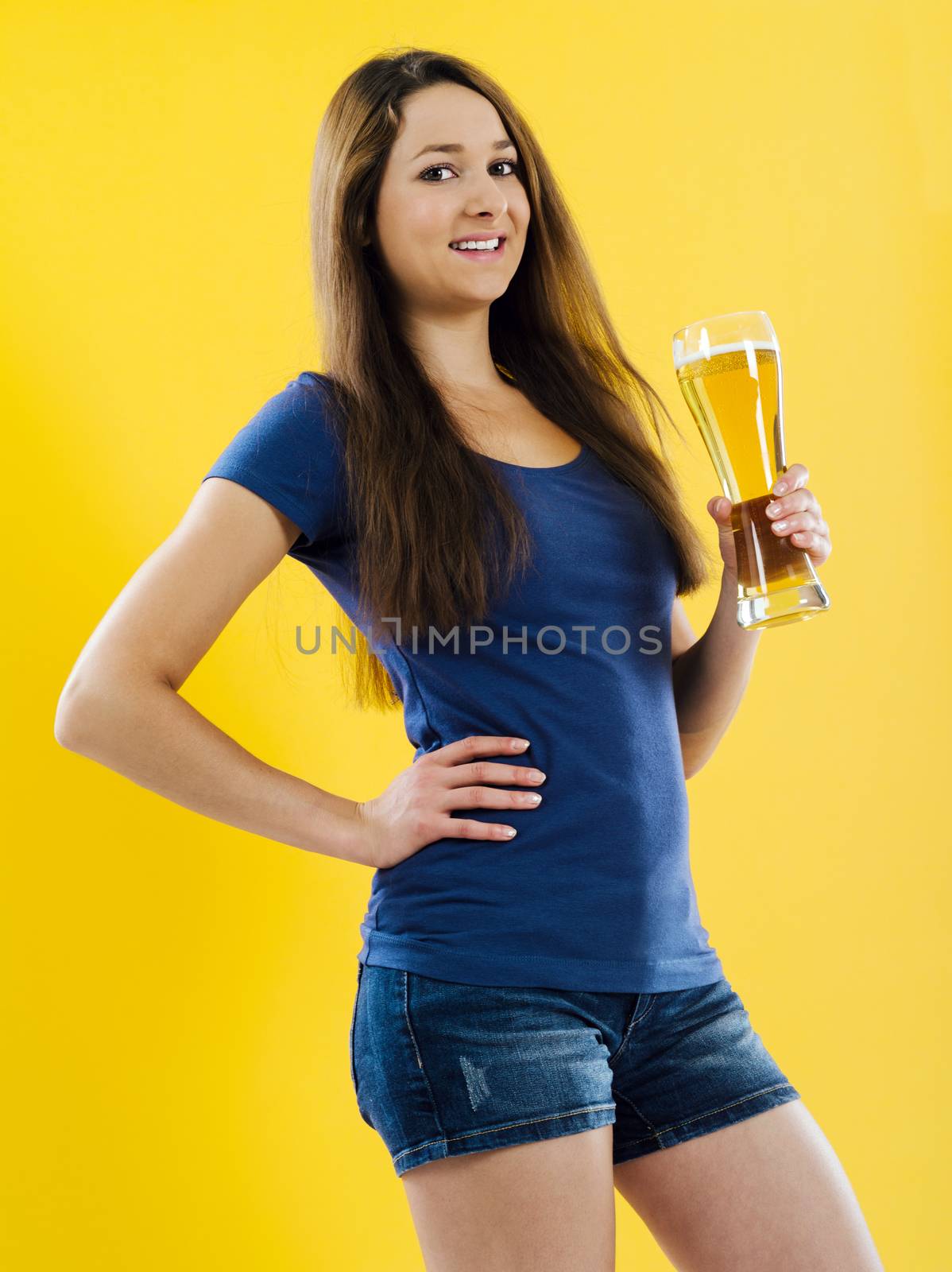 Photo of a beautiful young brunette woman drinking beer from a tall glass.
