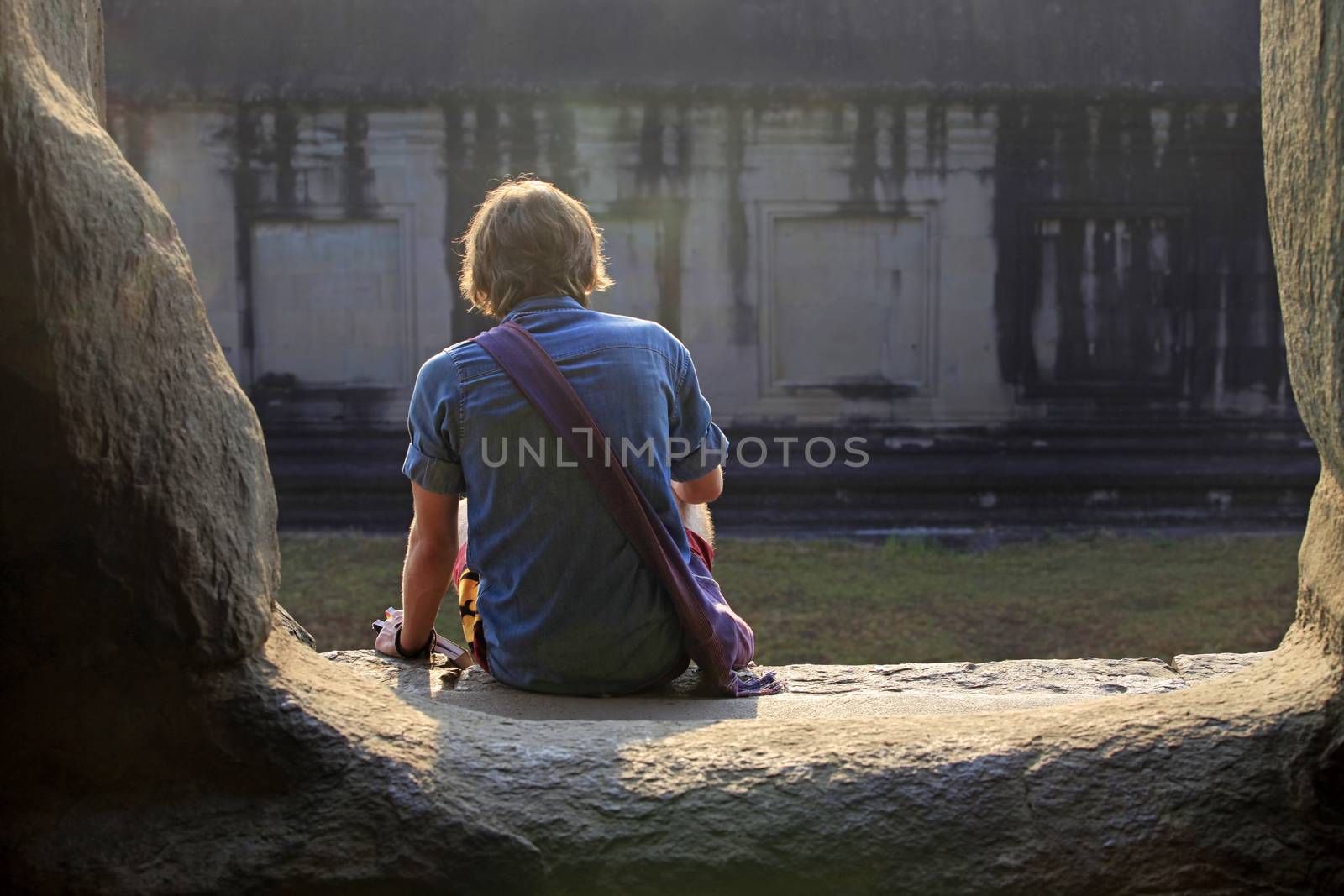 Young man with a book in the ruins of Angkor Wat