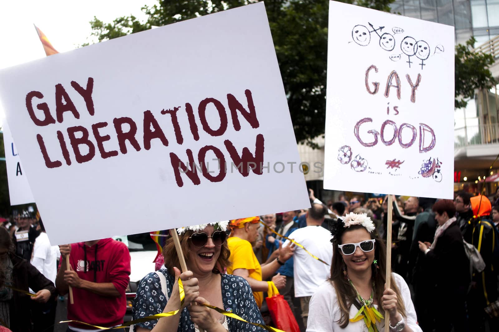 BERLIN, GERMANY - JUNE 21, 2014:Christopher Street Day.Crowd of people participate in the parade celebrates gays, lesbians, bisexuals and transgenders.Prominent in the image a two participant with placards.