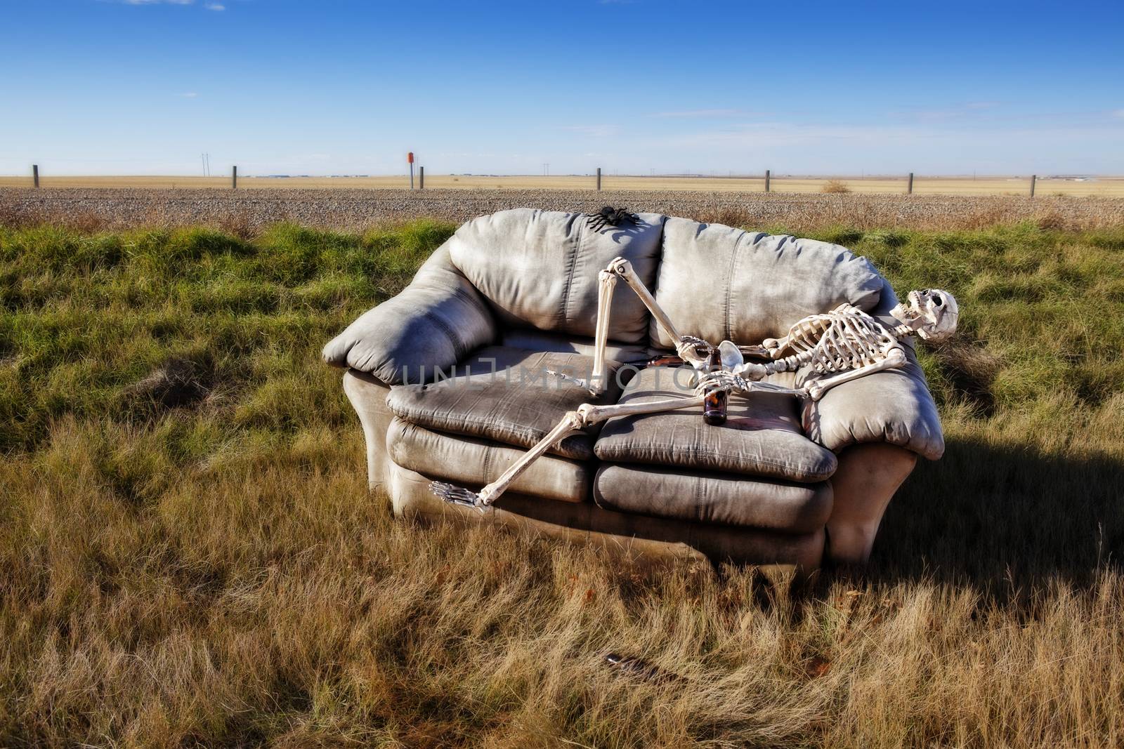 A beer stained party couch haunted by parties past, discarded in a ditch on a rural prairie road.