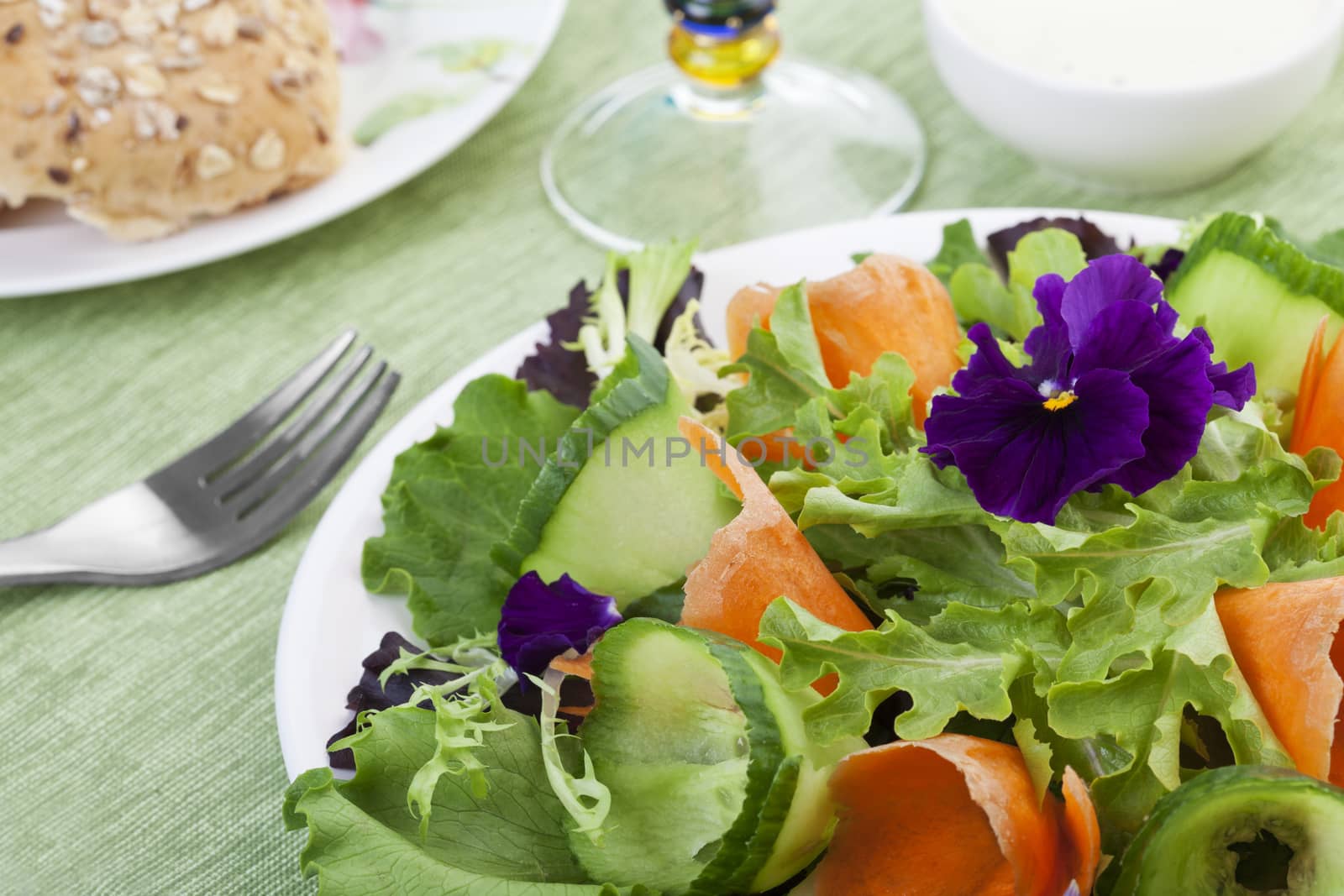 Various baby greens form the base of this salad, with carrot and cucumber curls adding color and texture.  Edible pansy flowers add the finishing touch to this fresh spring eating experience.