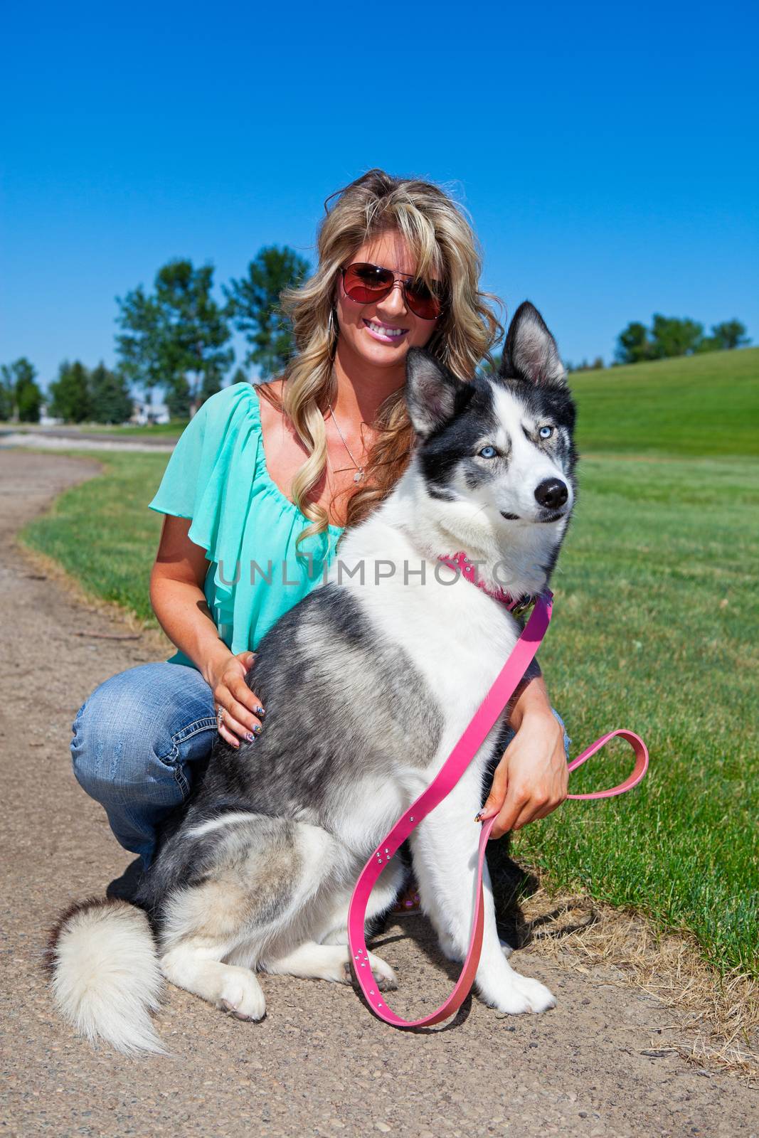 A young woman with her female American Husky dog on leash.