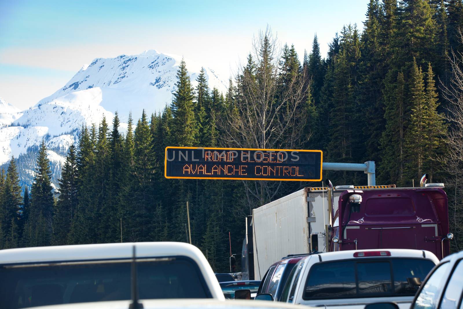 Travel through Roger's Pass in spring.  Traffic is stopped while avalanches are triggered with explosives and then cleaned from the road to ensure safe travel. Roger's Pass, British Columbia, Canada.