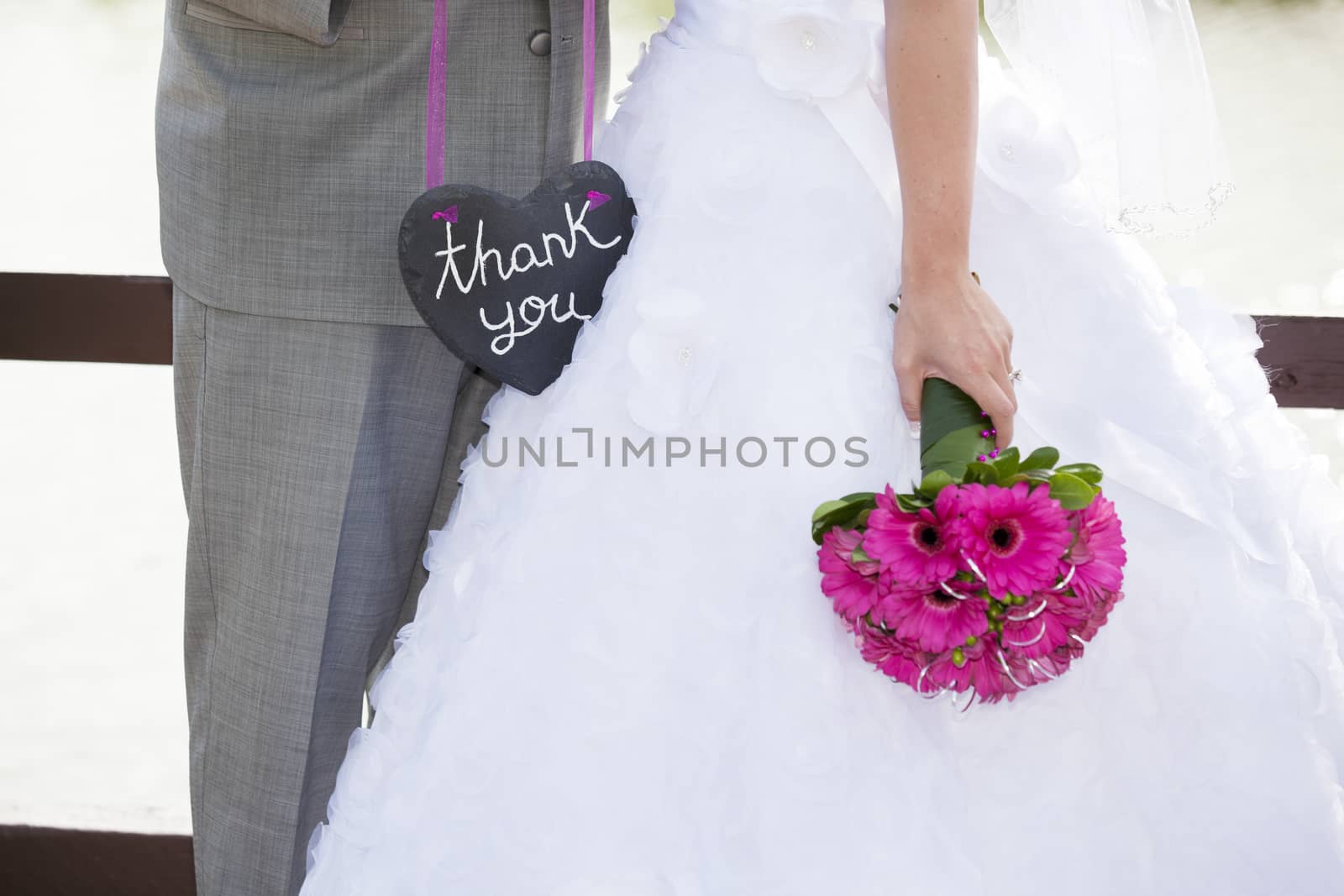 A bride and groom holding a heart shaped thank-you sign.