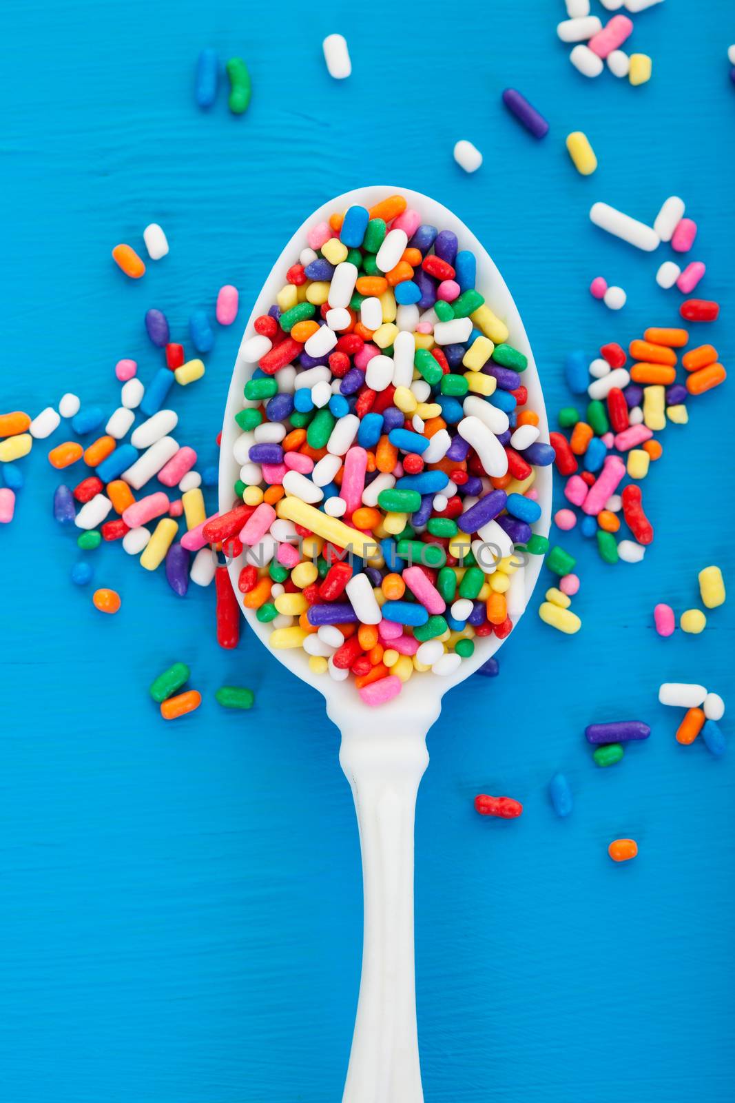 Old spoon overflowing with candy sprinkles. Macro.