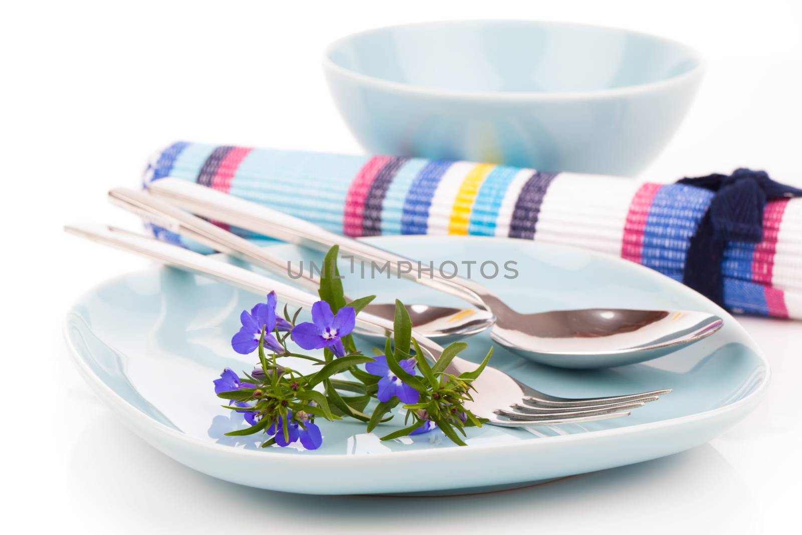 tableware with blue lobelia flowers and cutlery, on a white background.
