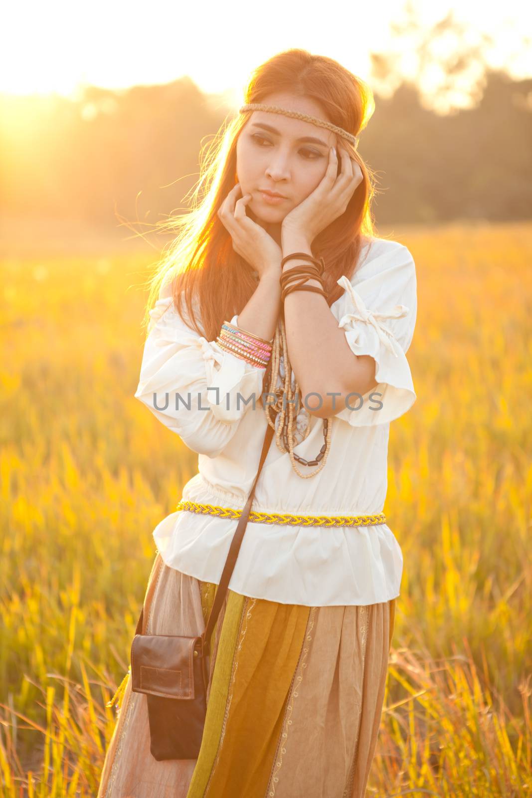 Hippie woman posing in golden field on sunset