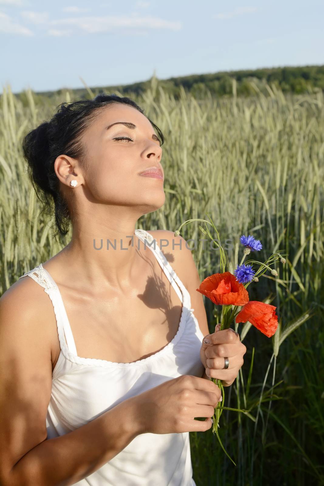 dreamy young  woman with bouquet in cornfield