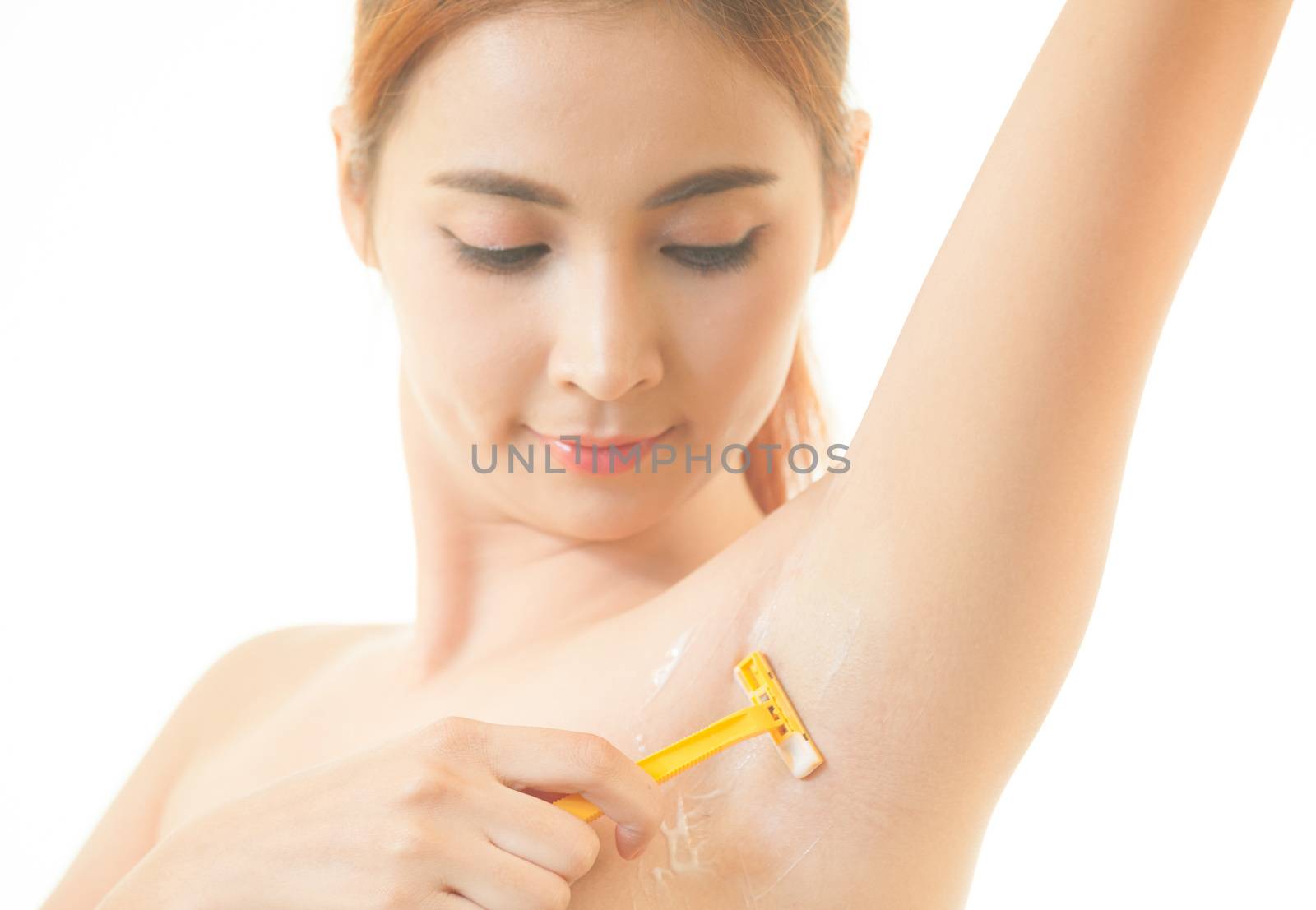 Young asian woman shaving armpit with razor isolated on white background