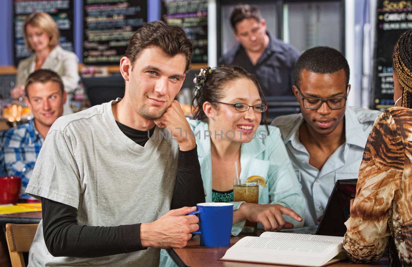 Confident Caucasian male student with friends in cafe